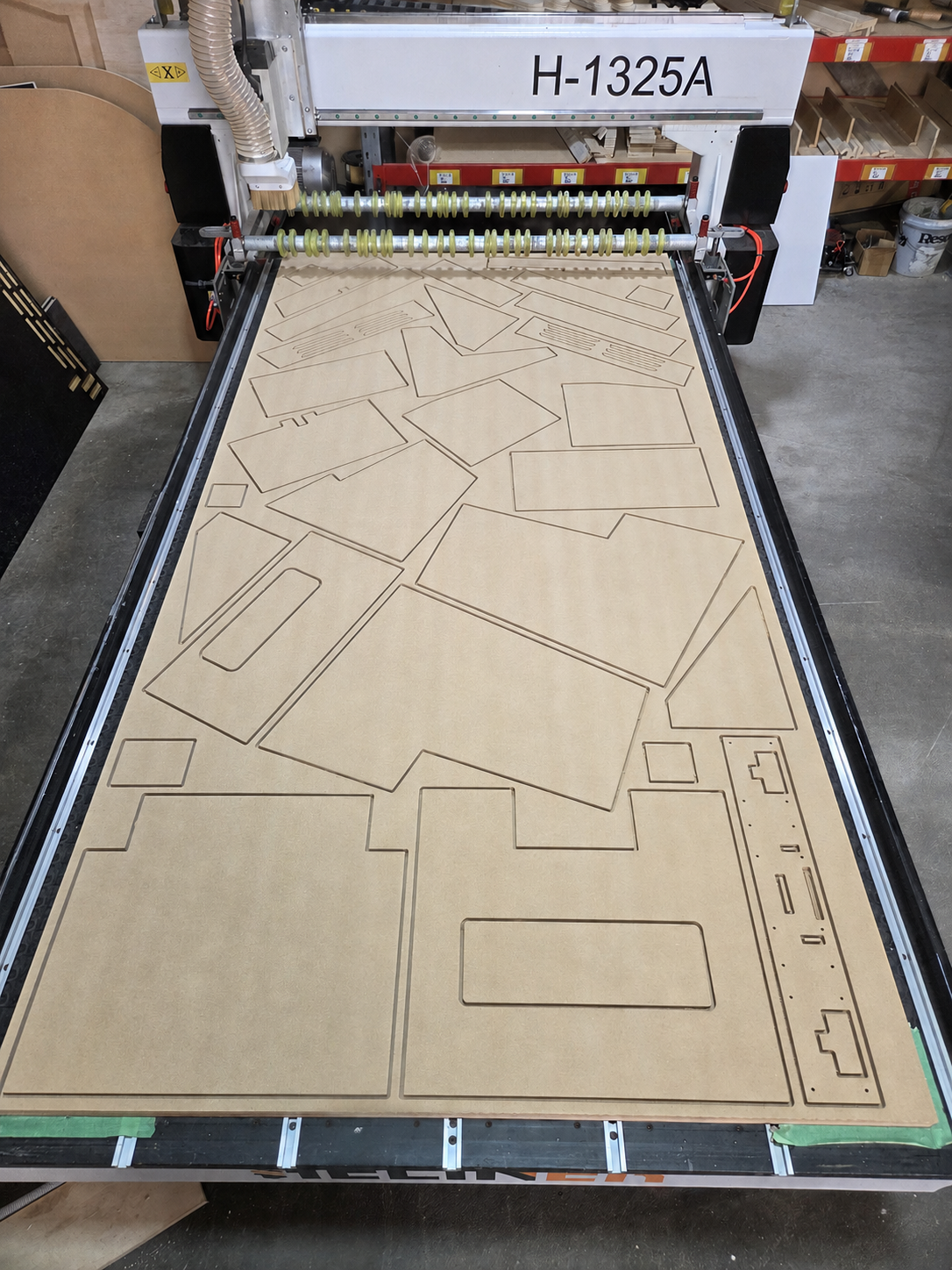 CNC machine cutting various shapes out of a large piece of wood.