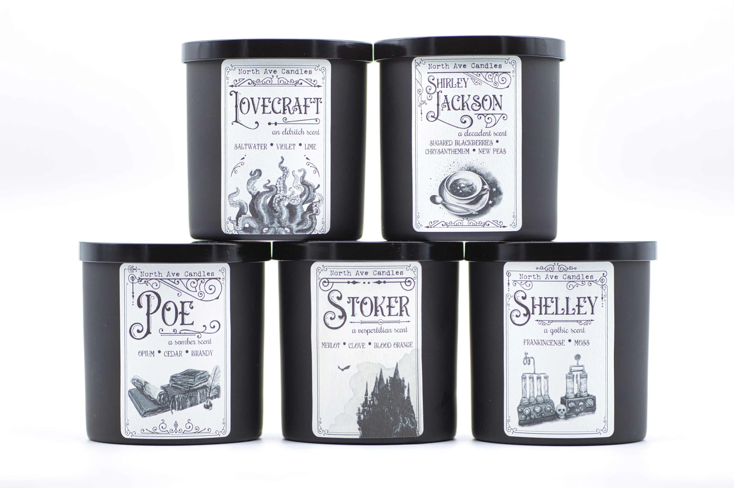 Six black candle tins with white labels featuring gothic-style illustrations and text, stacked in two rows of three against a white background.