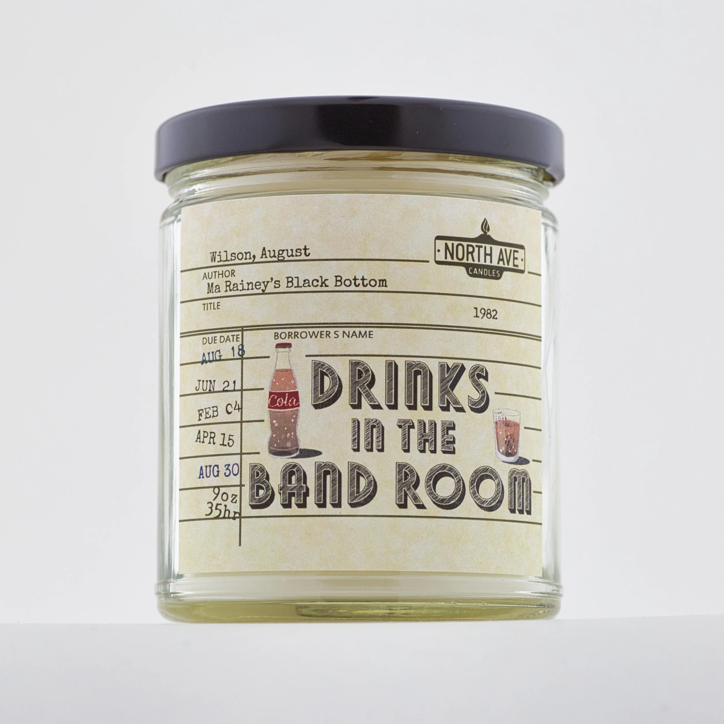 A candle jar with a drink-themed label including a vintage style illustration of a cola bottle and a glass of soda, with text about drinks and band room.