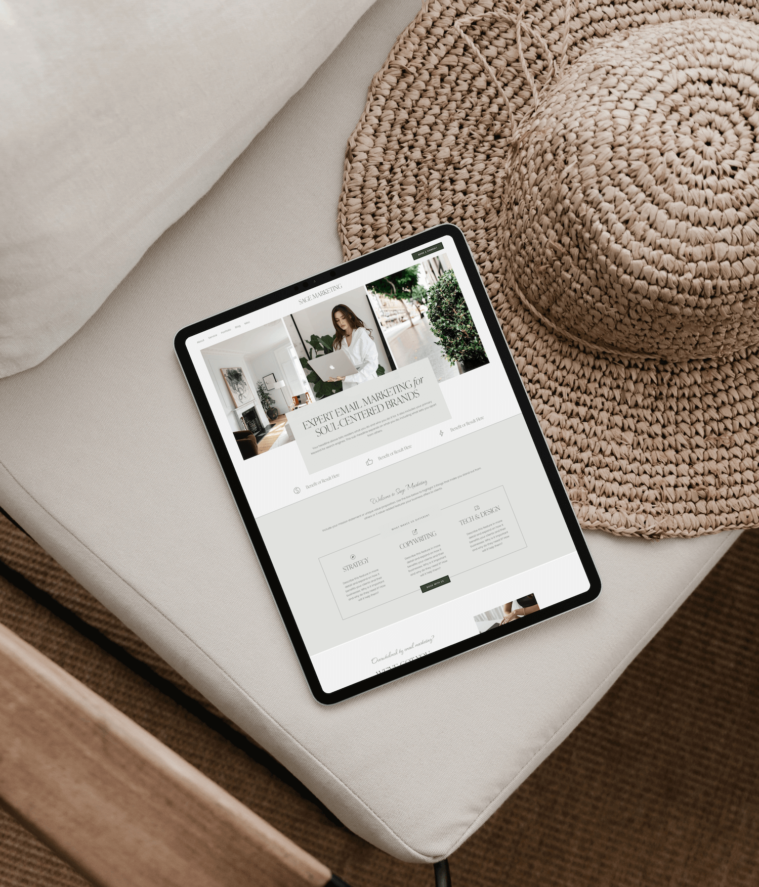 An iPad displaying a website about email marketing placed on a beige sofa next to a woven straw hat and a round woven mat.
