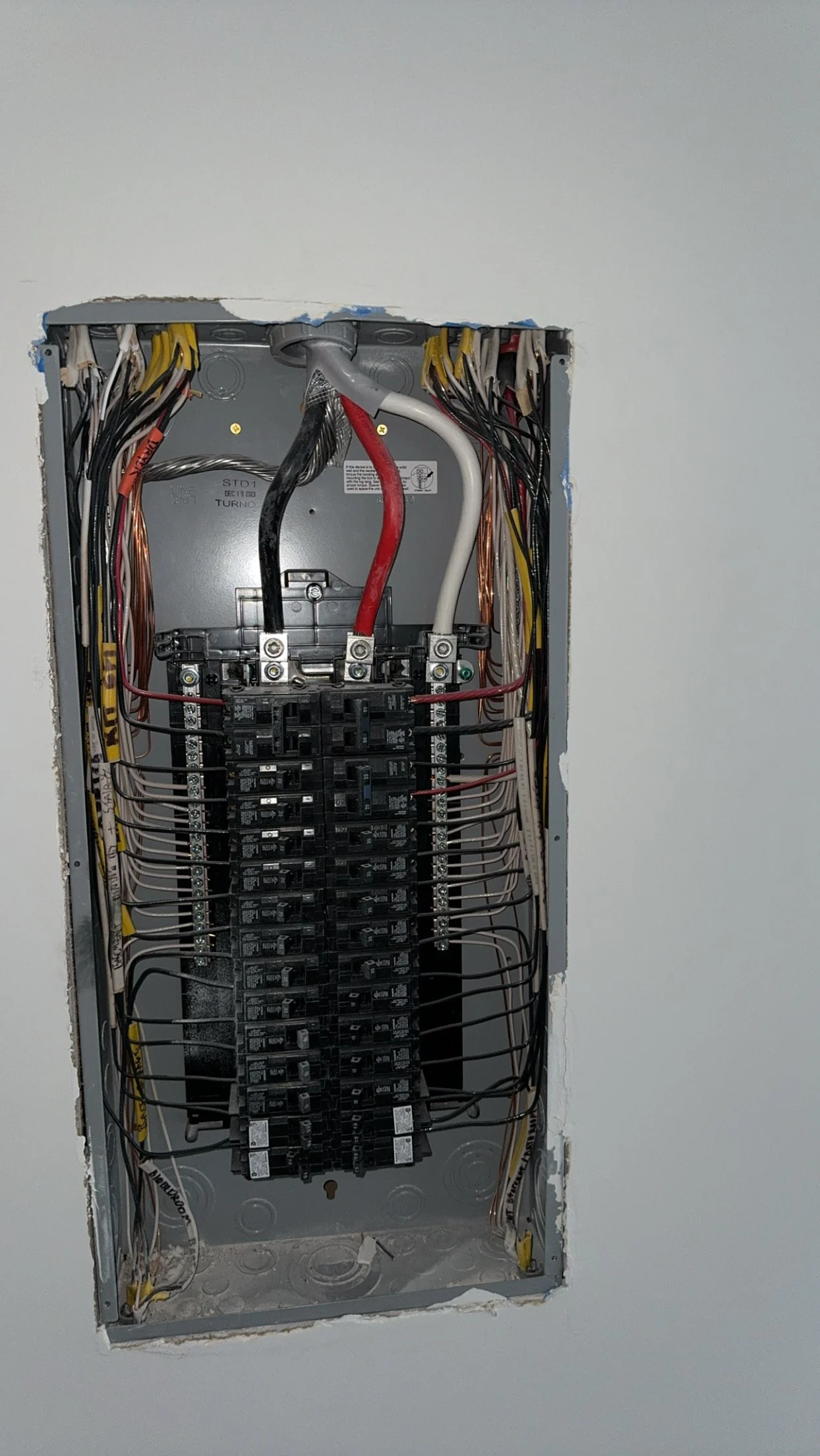 Inside an electrical panel with multiple wires connected to circuit breakers.