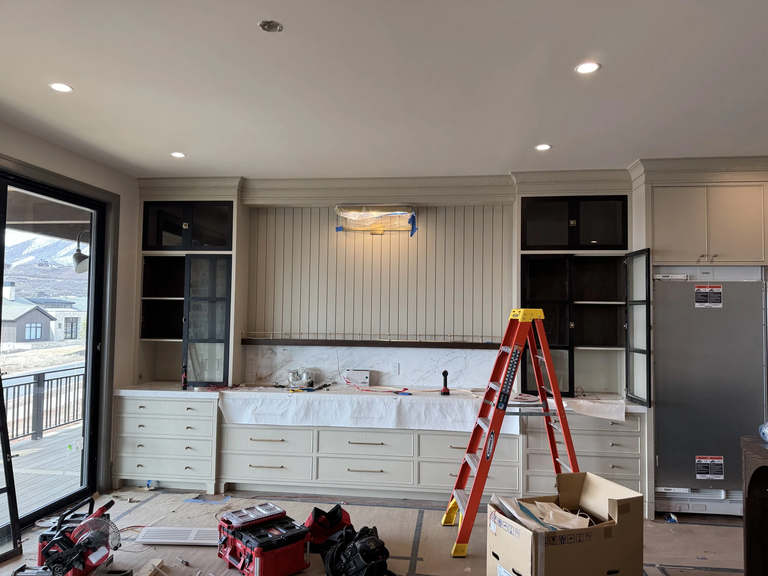 Kitchen led lighting with open cabinets, tools, ladder, and construction materials.