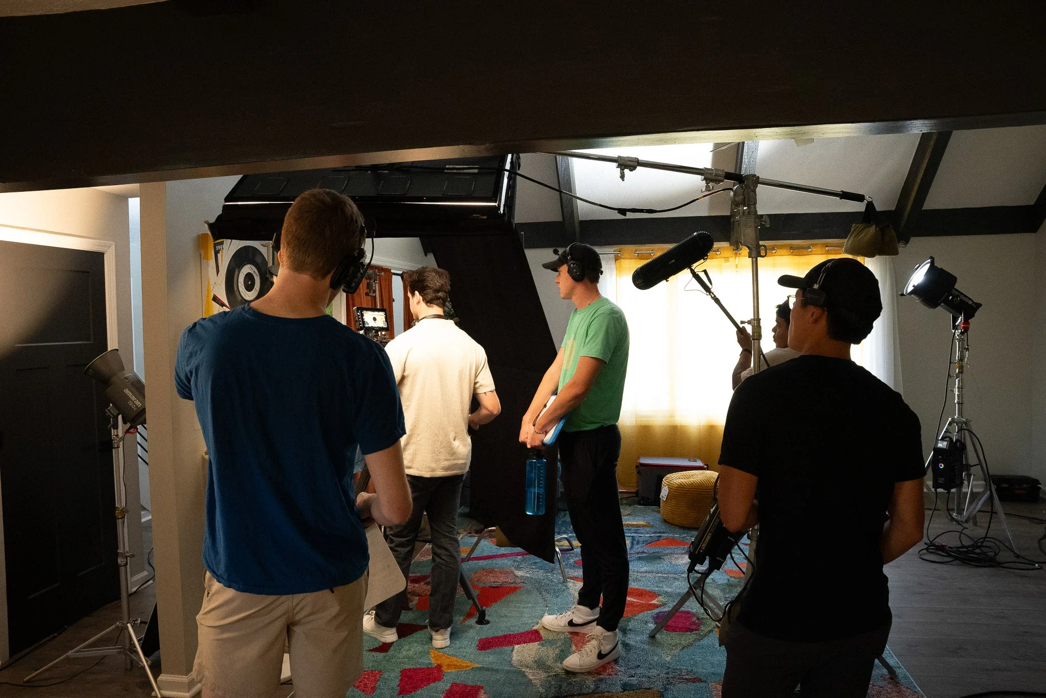 Filming crew working on a video shoot in a home studio with professional lighting, cameras, and sound equipment.