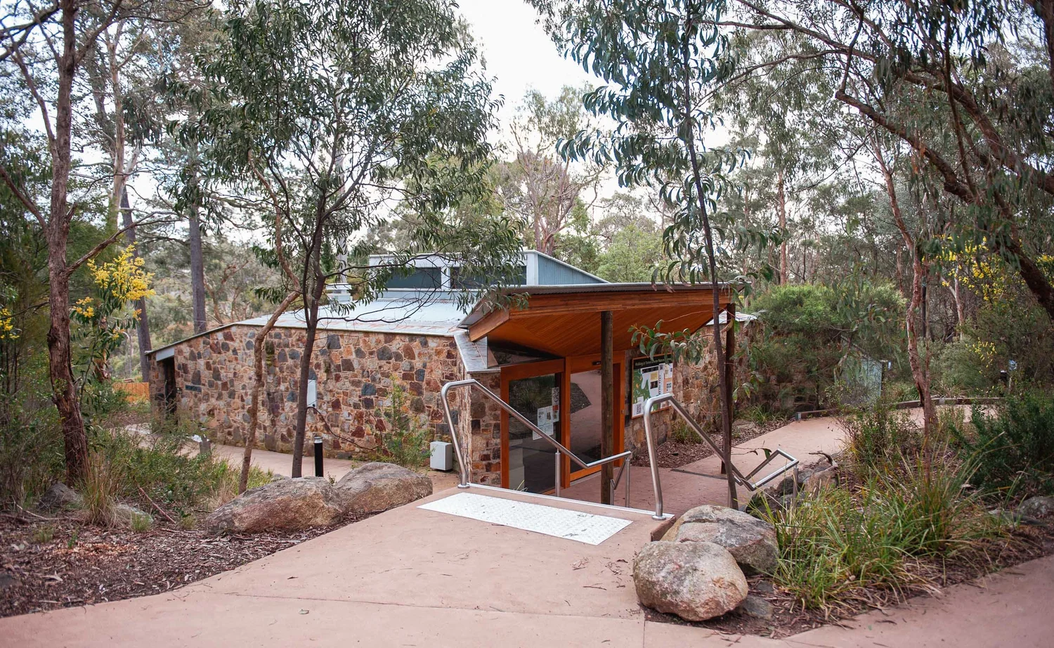 A yellow A-frame sign reading Information Centre Open, Visitors Welcome, standing on the path outside the Yarran Dheran Information Centre.