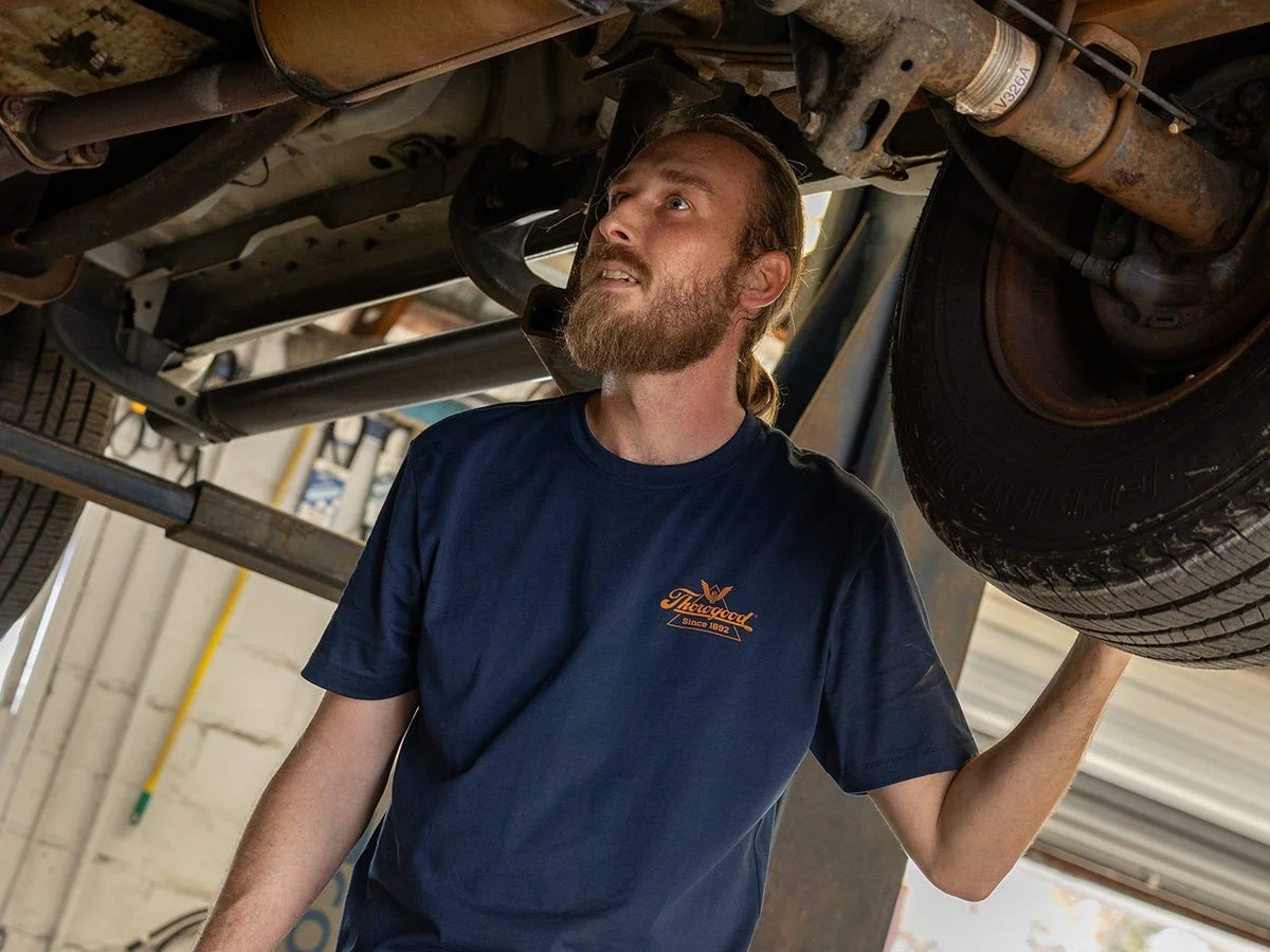 Mechanic under a truck on a vehicle lift performing repairs or inspections.