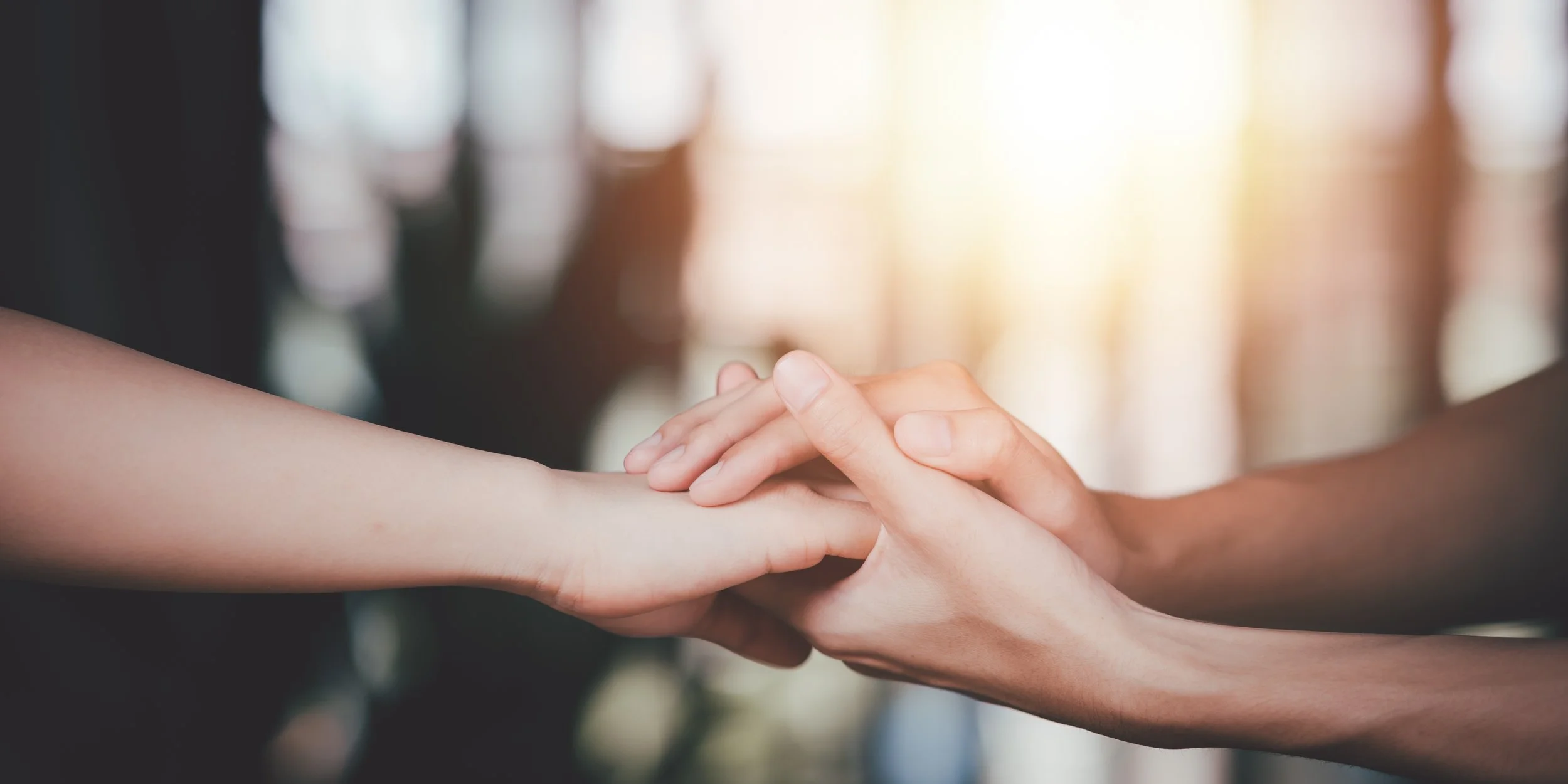 Two people holding hands in a gentle, supportive gesture.
