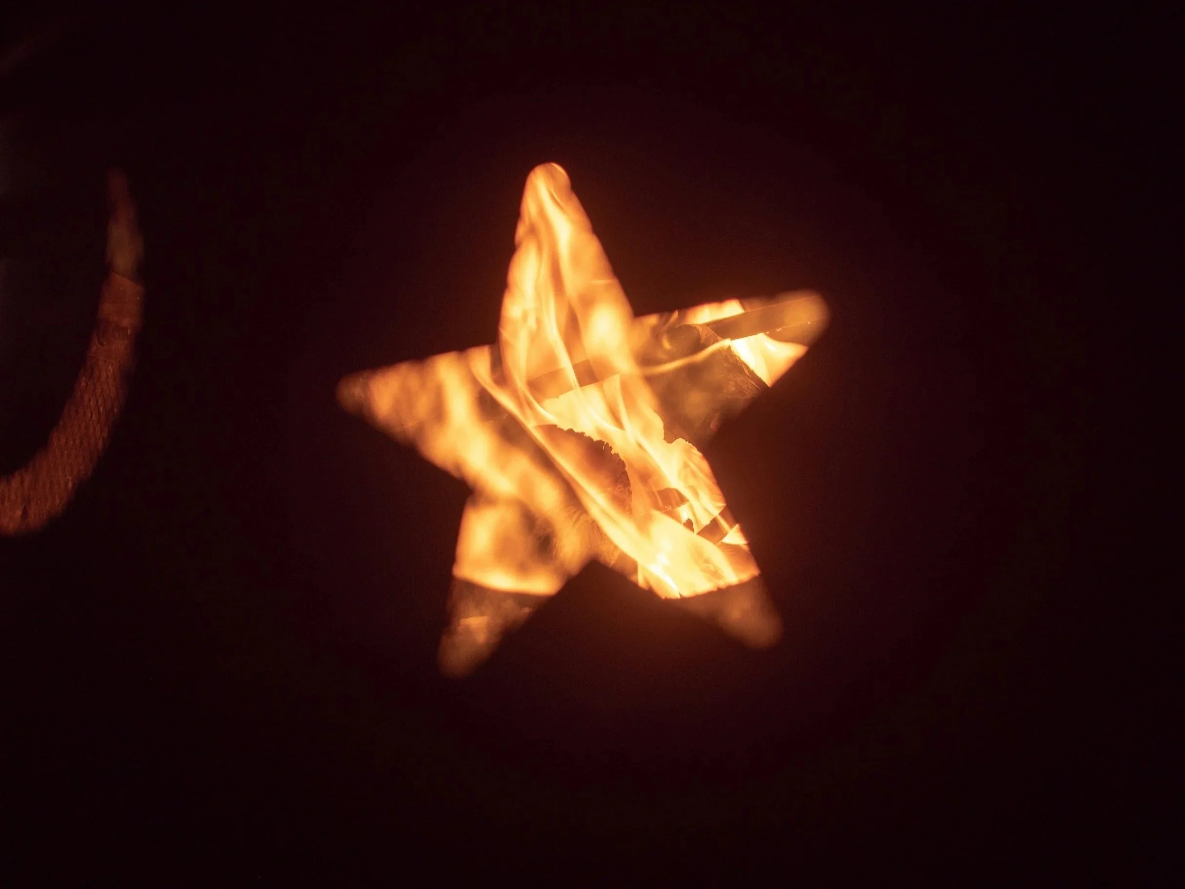 A star-shaped object with burning flames inside it, against a dark background.