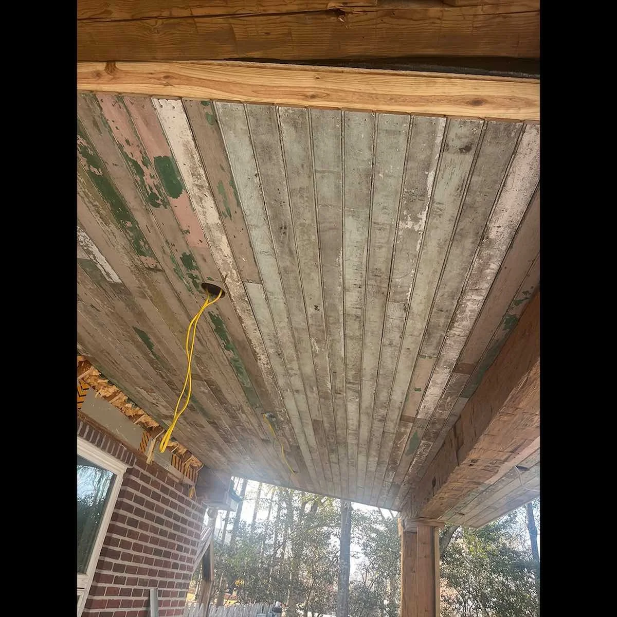 Installed antique reclaimed bead board ceiling showing aged chipped paint and weathered character.