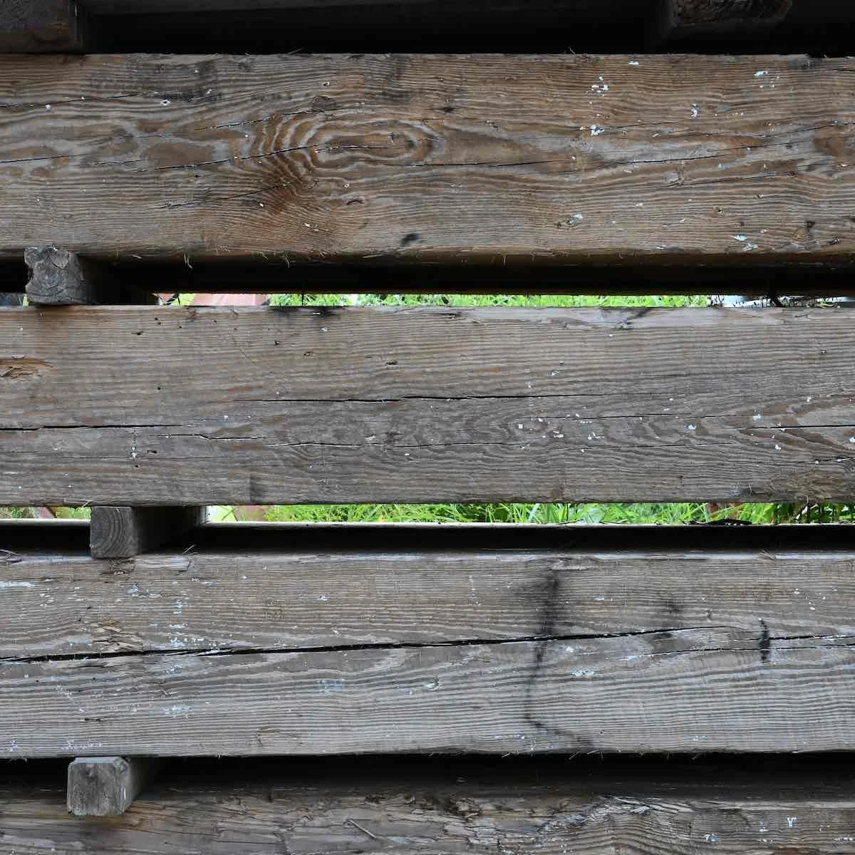 Antique reclaimed industrial timbers with natural patina, weathered grain, and historic character stacked outdoors.