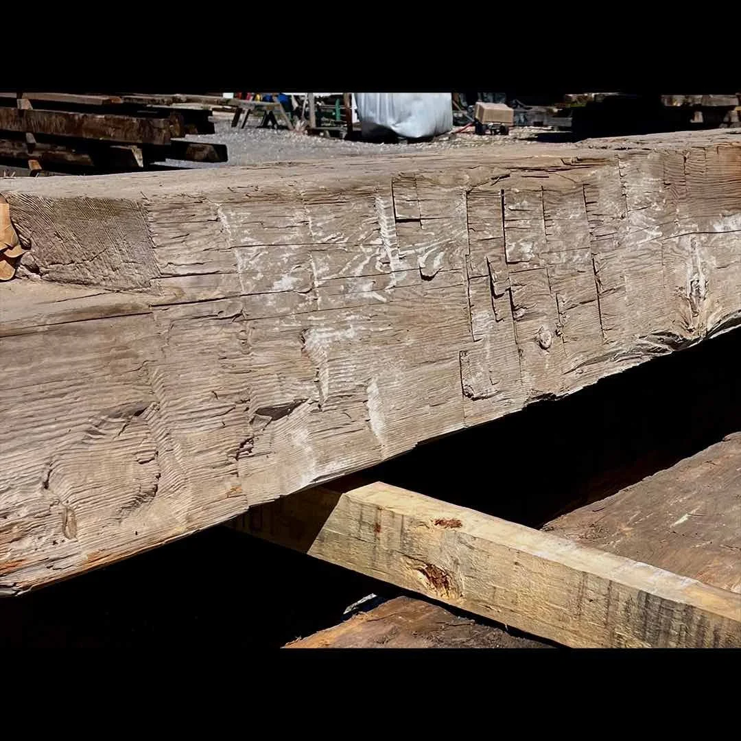 Close-up antique reclaimed hand-hewn timber showing tool marks, natural patina, and aged texture.