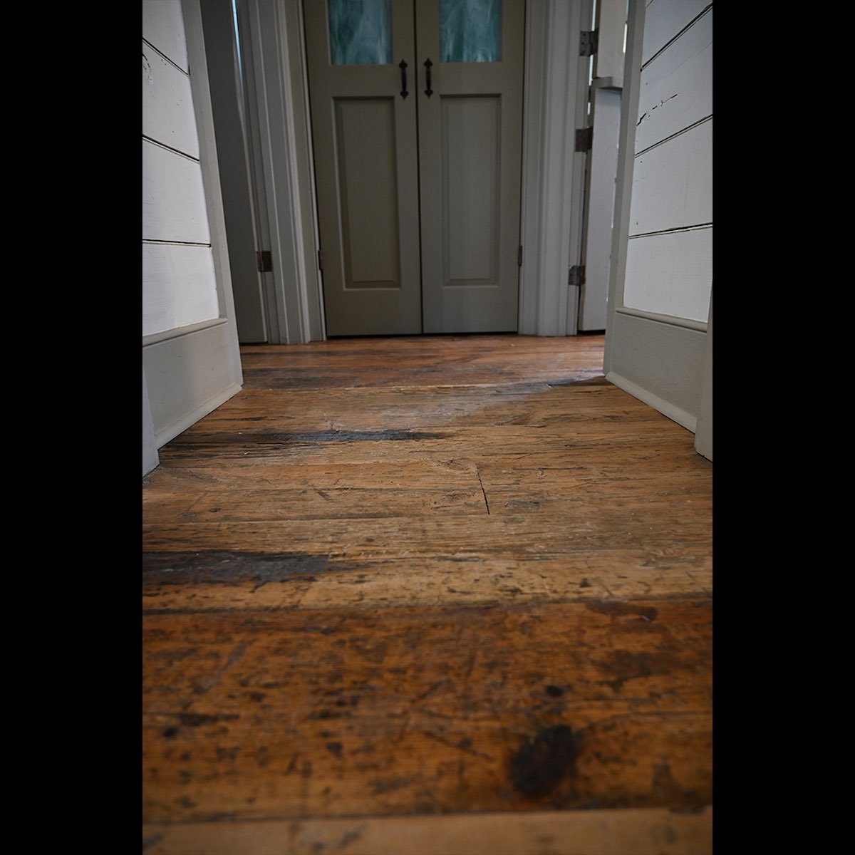 Antique reclaimed tidewater cypress client installation featuring warm-toned wooden door and matching wall paneling with rich grain detail.