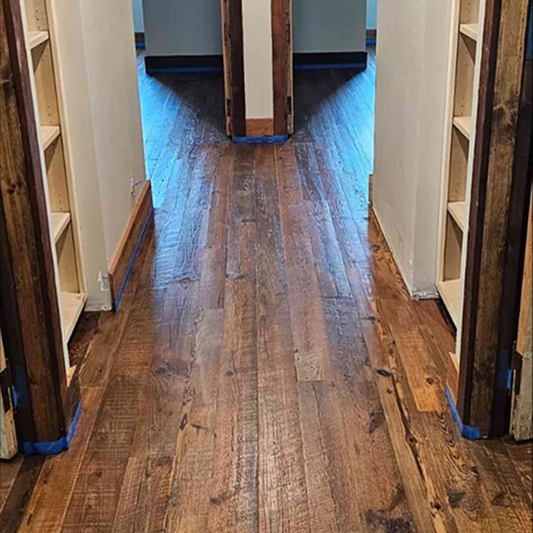 Reclaimed antique wood flooring installed in a hallway, showcasing rich patina, natural grain, and aged character.