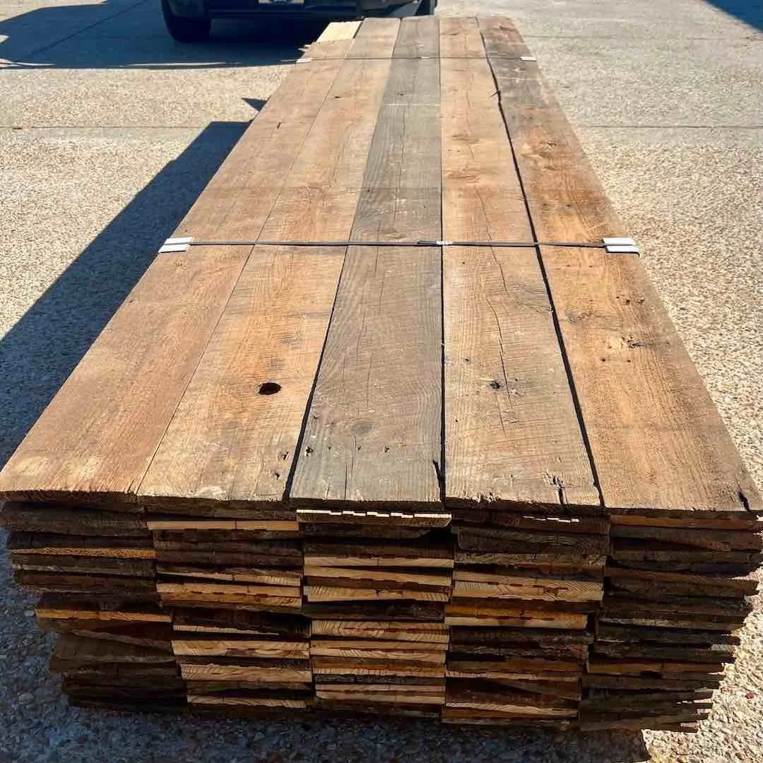 Stacked antique reclaimed unfinished boards, showing natural patina, weathered textured, and tool marks.