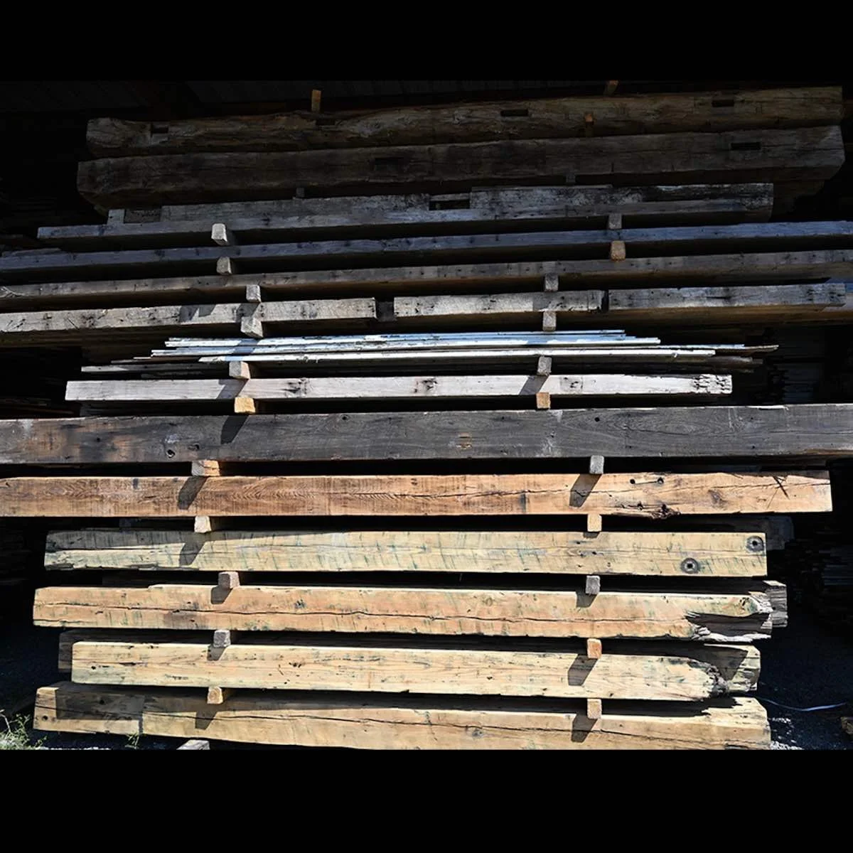 Stacked antique reclaimed industrial timbers with aged patina, saw marks, and varying dimensions.