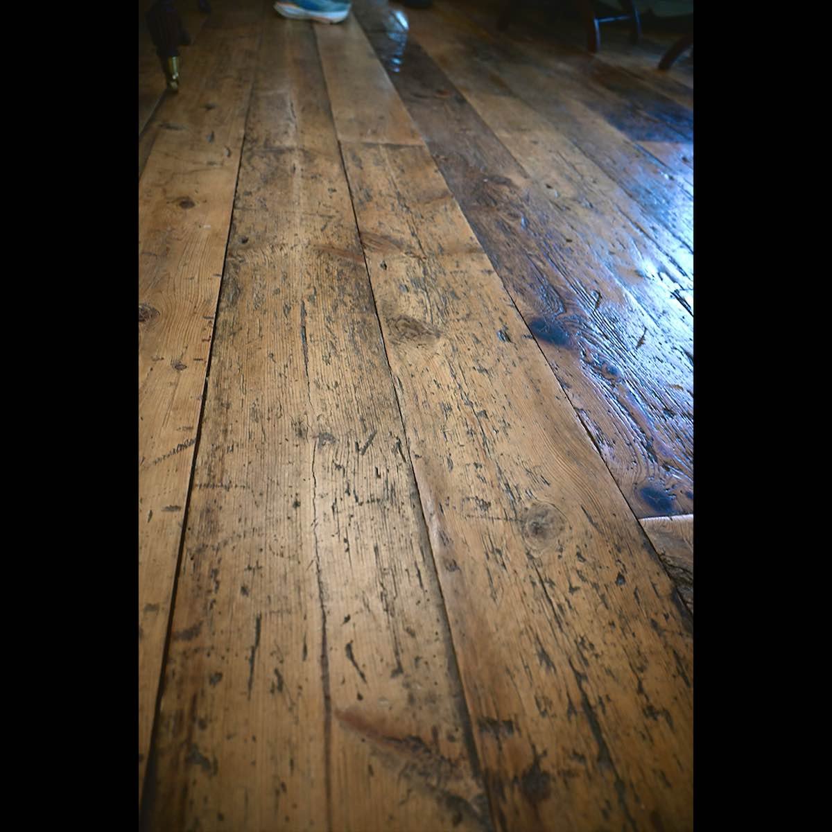 Antique reclaimed foot-worn white pine flooring installed in a client's home, showcasing rich patina and authentic wear marks.