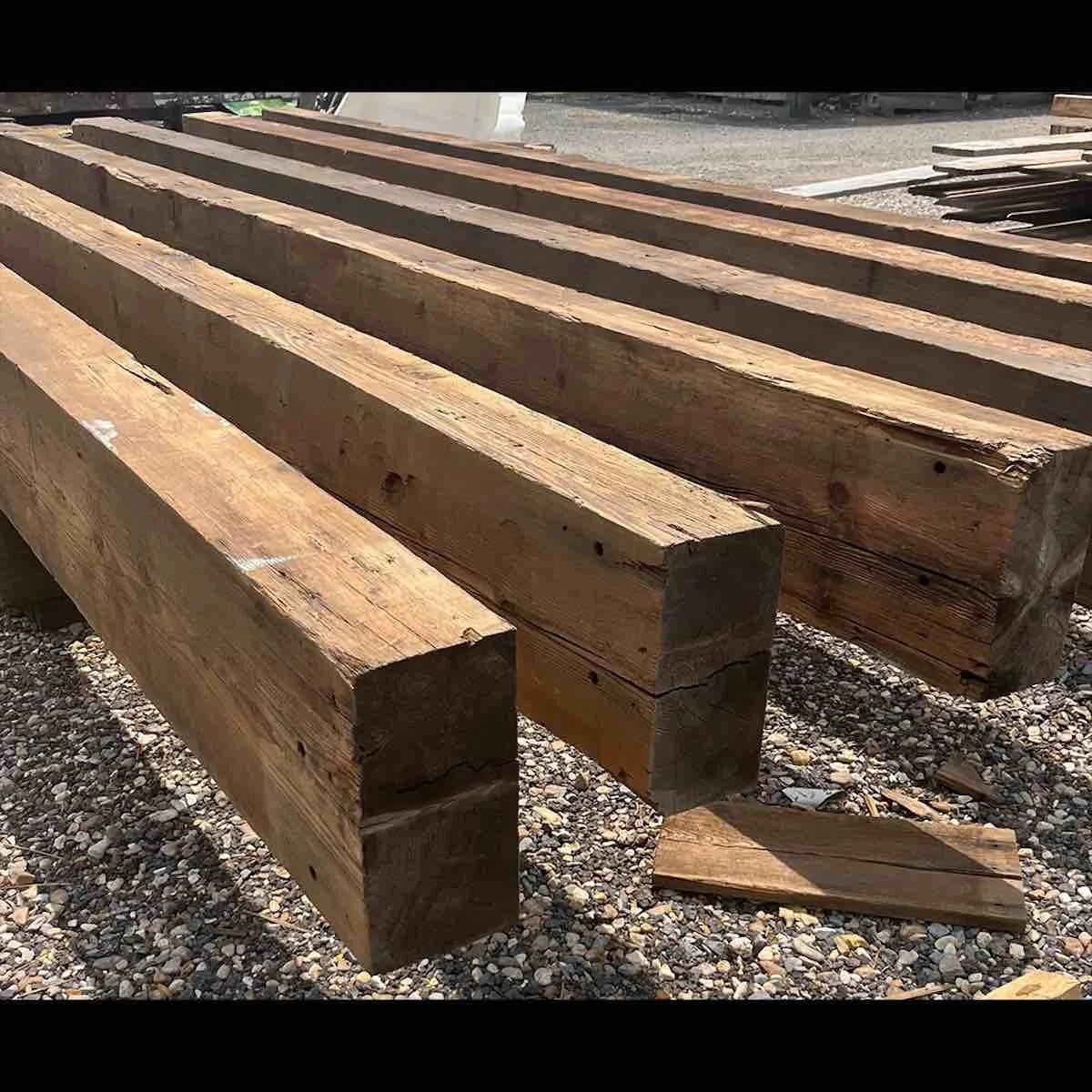 Stack of antique reclaimed industrial timbers with straight edges, patina, and aged character.