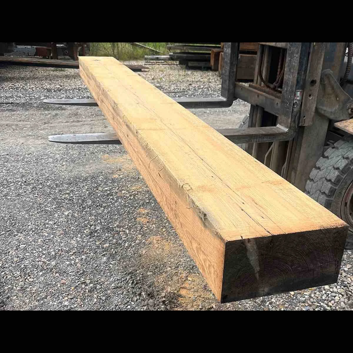 Resawn antique reclaimed industrial timber beam with visible old-growth grain, displayed on a forklift in a lumber yard.