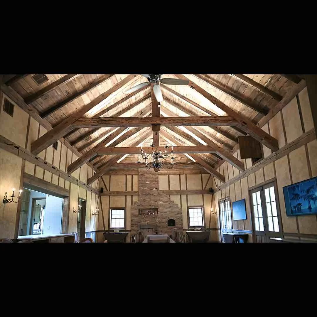 Thumbnail of client's home interior with exposed antique reclaimed hand-hewn timbers in vaulted ceiling above brick fireplace.
