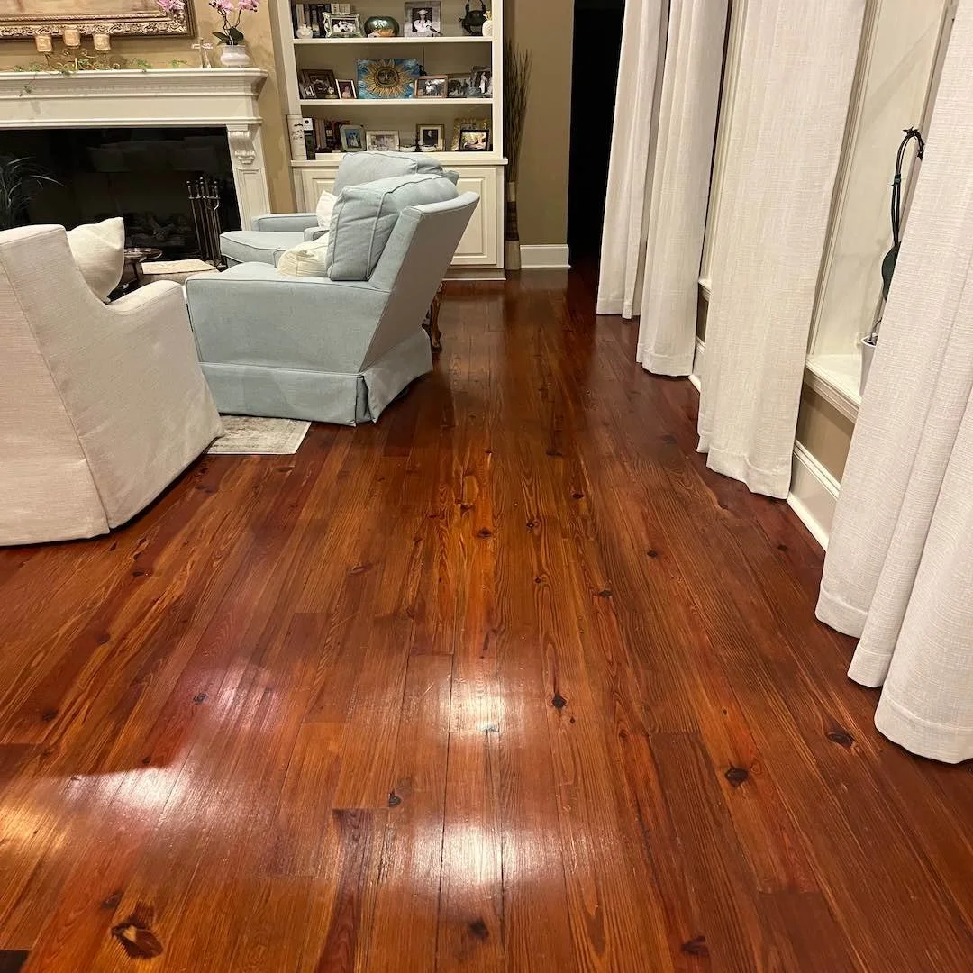 Finished antique reclaimed longleaf pine flooring in a client's living room, showing rich patina, natural grain, and warm sheen.