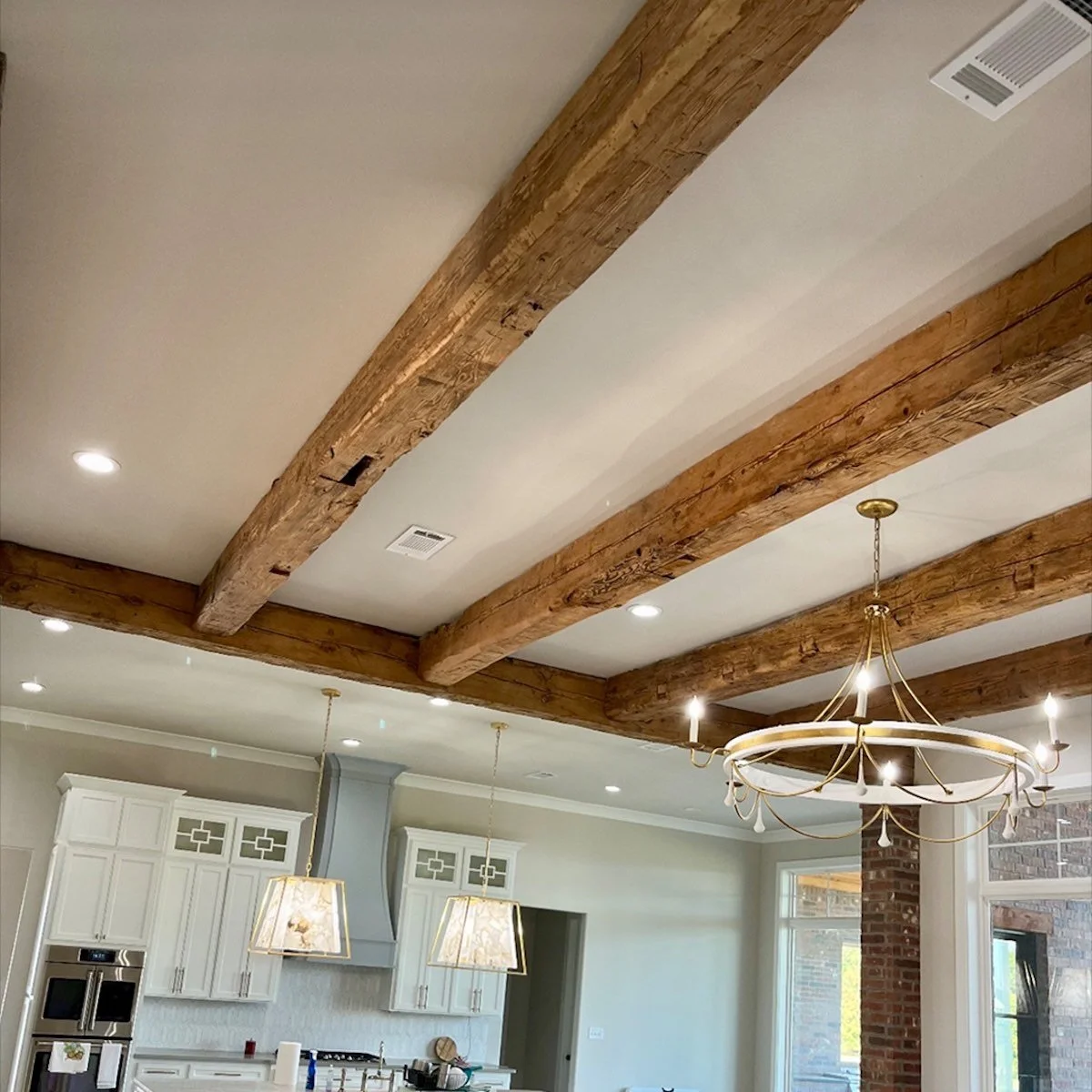 Client home kitchen with exposed antique reclaimed hand-hewn ceiling timbers, natural patina and tool marks, paired with modern lighting fixtures.