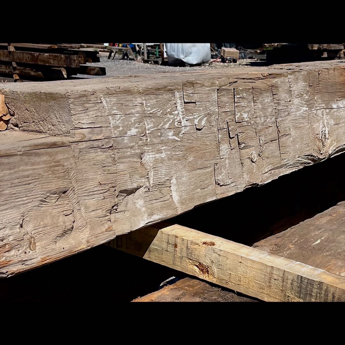 Antique reclaimed hand-hewn timber beam with visible tool marks, surface checking, and aged patina.