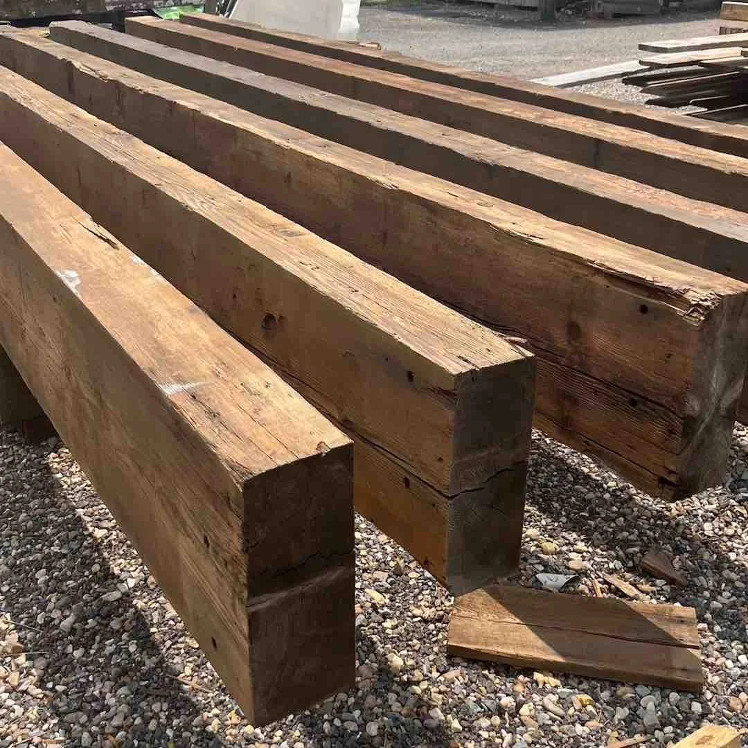 Antique reclaimed Douglas Fir industrial timbers stacked outdoors, showing aged patina, natural grain, and weathered texture.