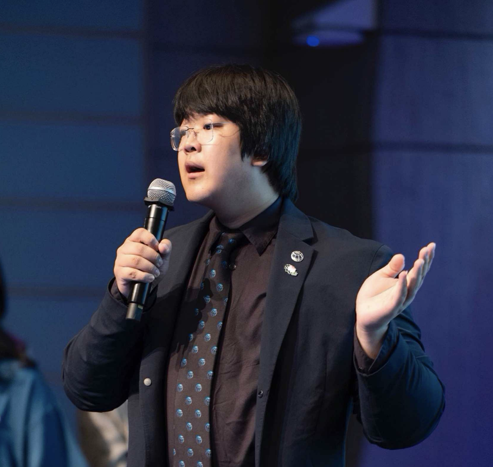 Zhijun He speaking at a podium