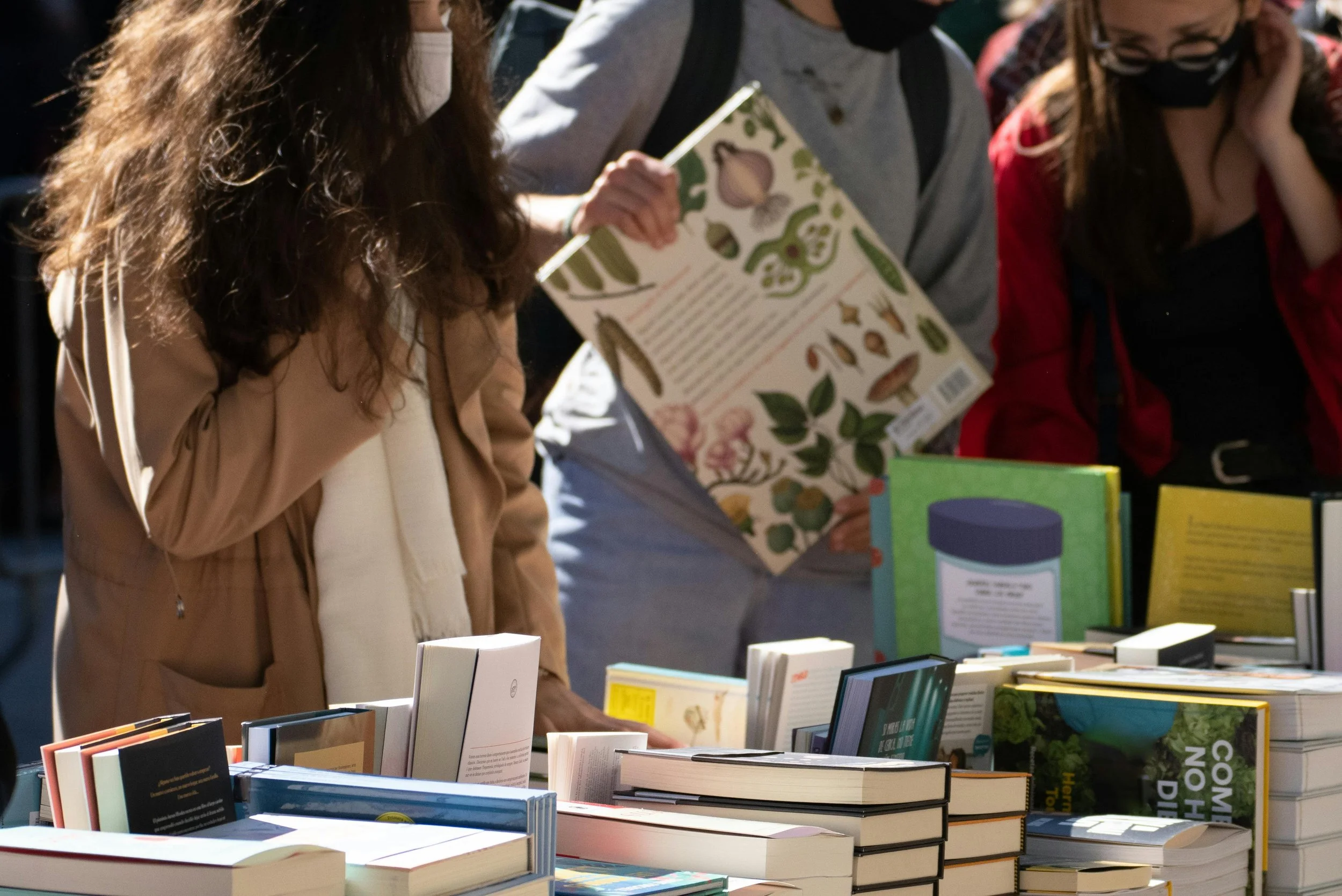 A person stands in front of a spread of books outside