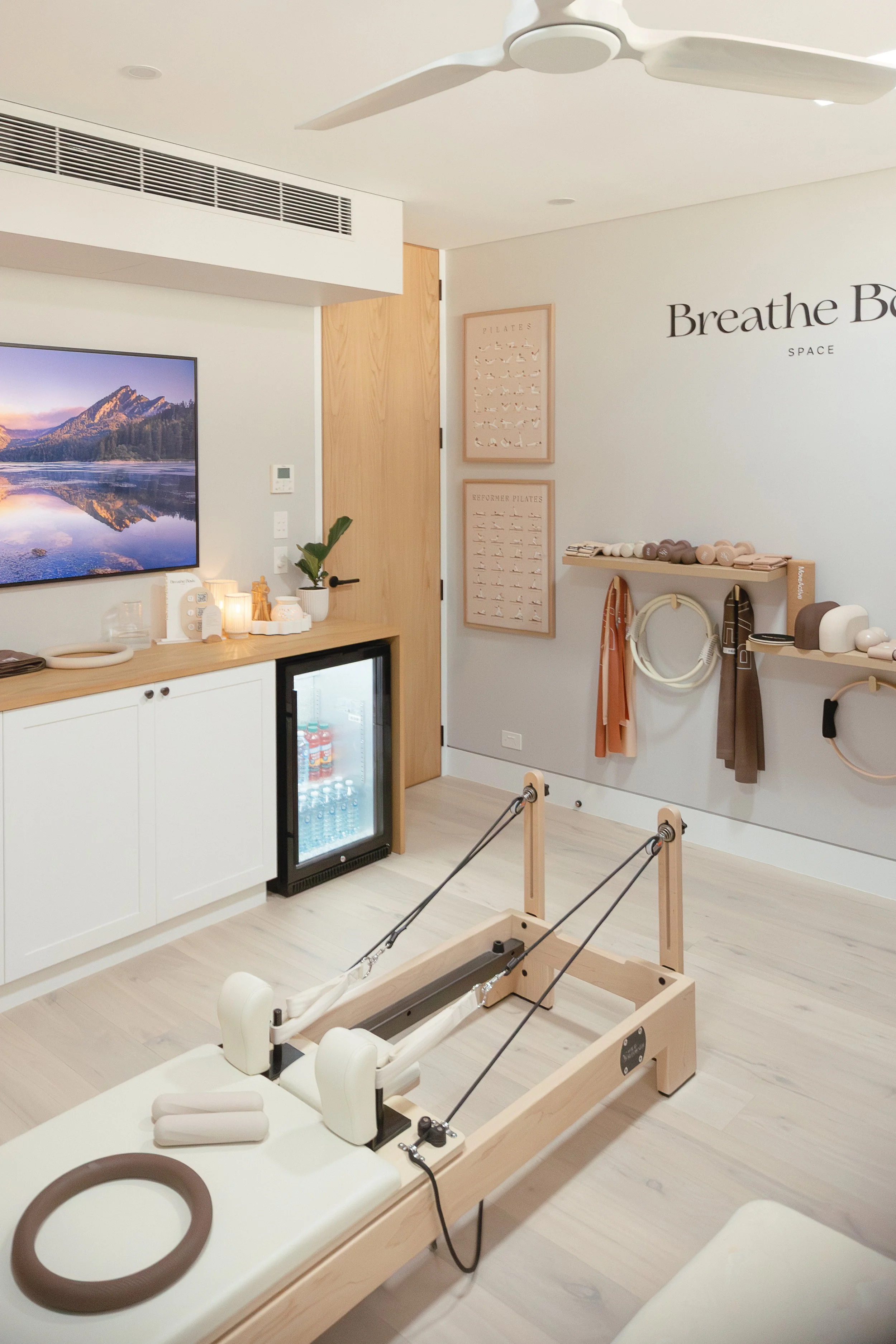 A Pilates studio with a reformer machine, wall-mounted Pilates equipment, designed with a neutral colour palette.