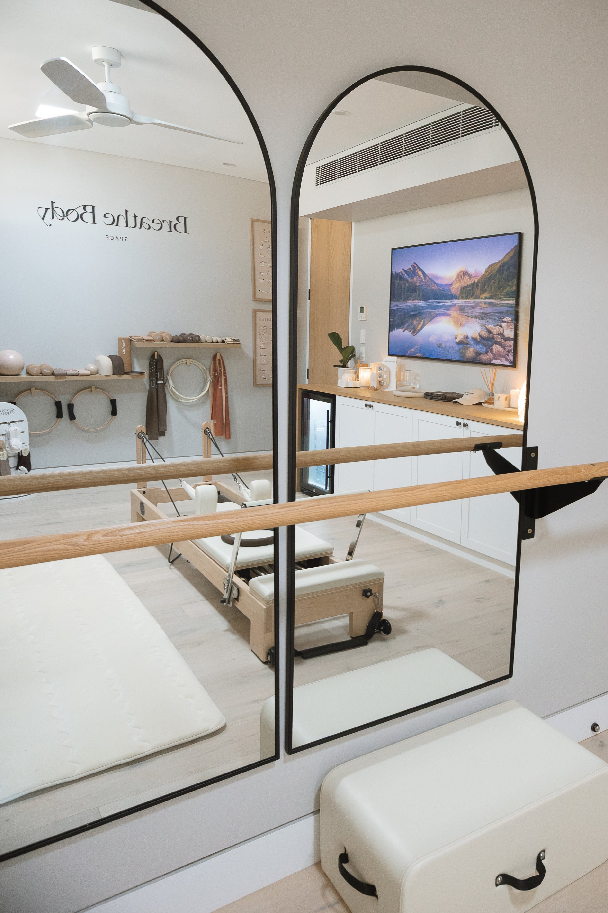 Interior of an at home pilates studio with a mirror, reformer pilates machine, wall mounted pilates equipment. 