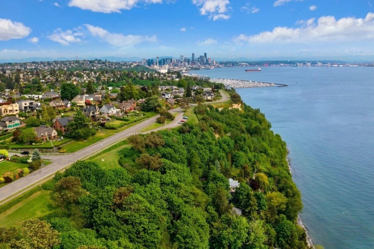 Aerial view of Seattle skyline with residential area, green trees, and waterfront with ships.