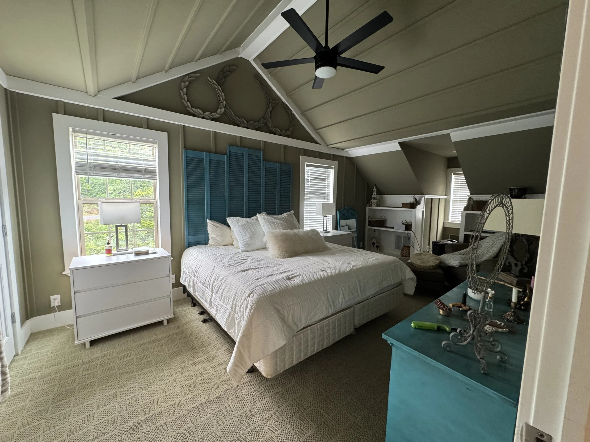 Clean, inviting bedroom with white bedding, ceiling fan, and teal furnishings in a vacation property.