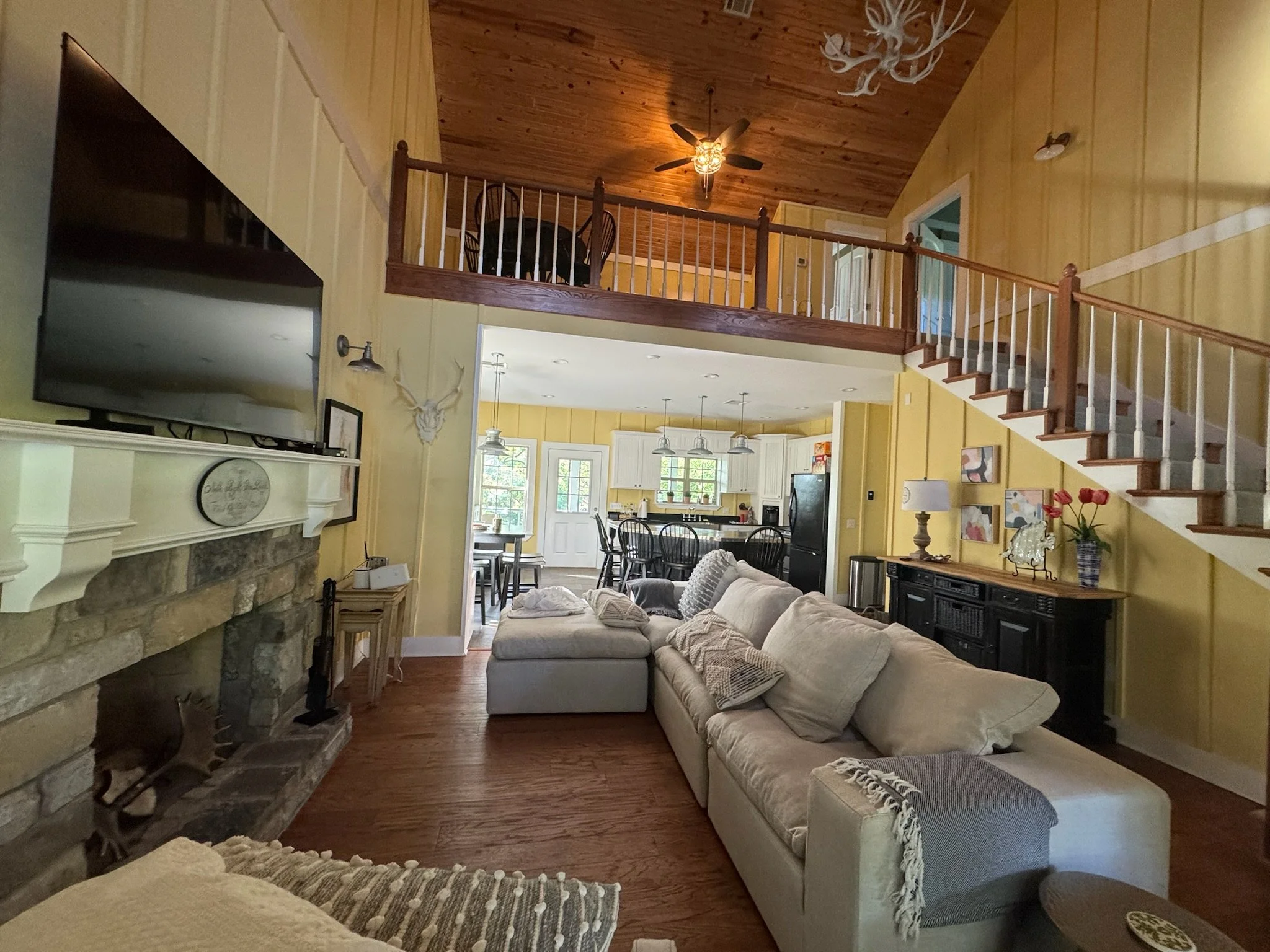 Spacious Lake Eufaula vacation home living room with vaulted wood ceilings, stone fireplace, and sectional sofa.