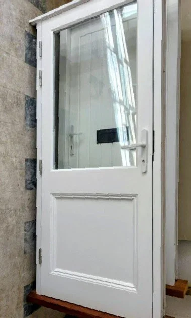 White exterior door with glass window and mailbox, installed outdoors near stone wall.