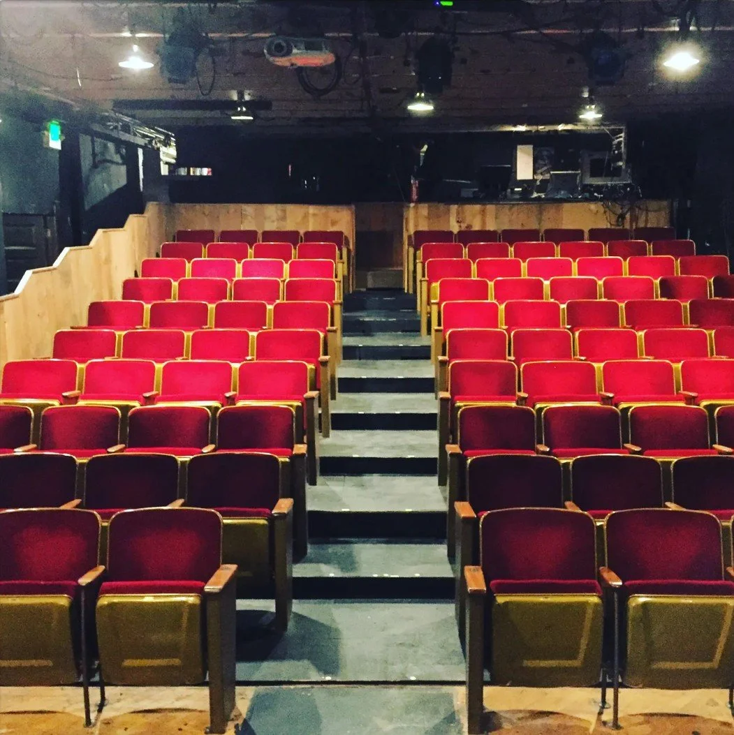 Picture of Annex Theatre house seats. Empty theater with red cushioned seats.