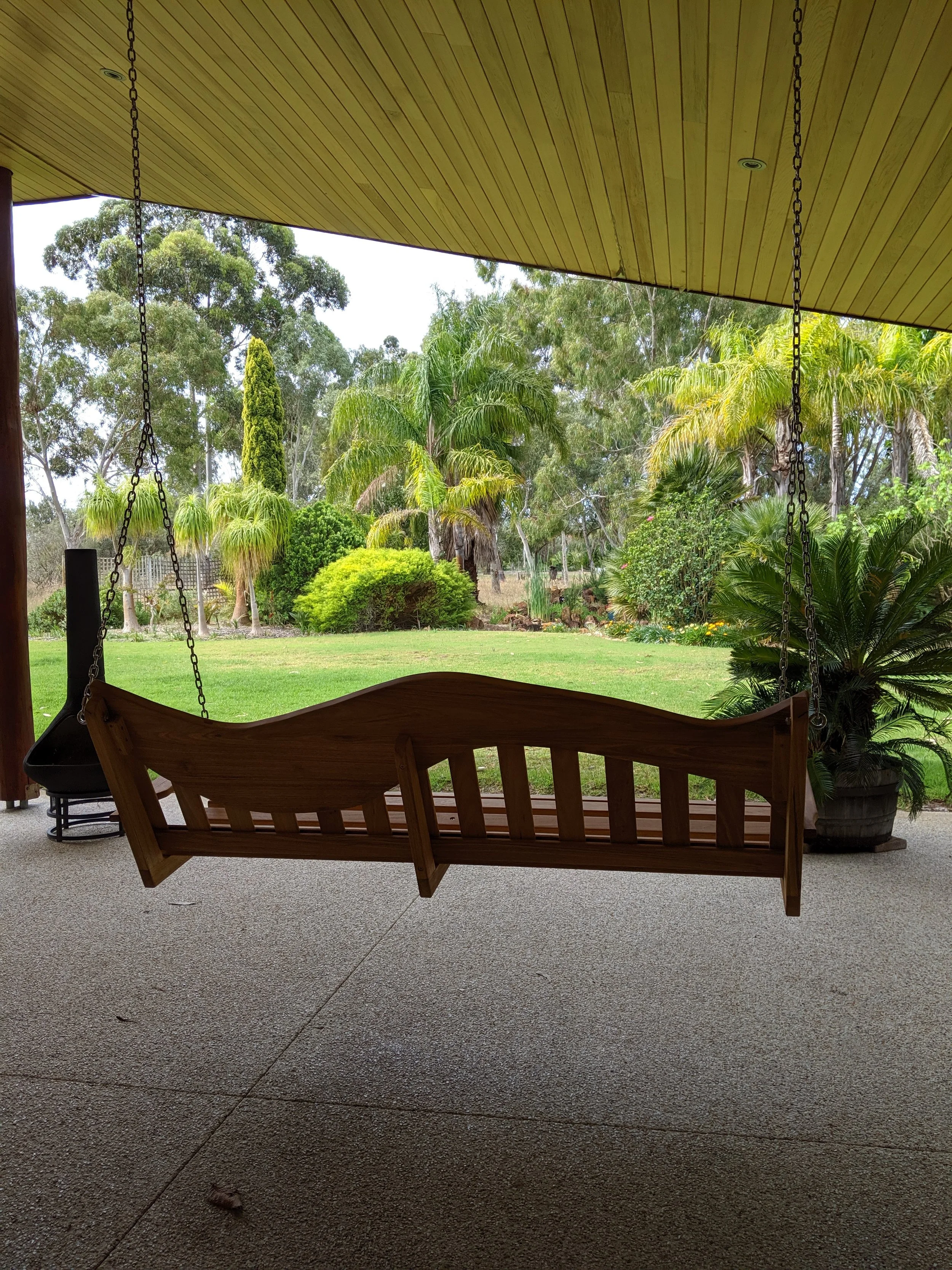 4 seat Jarrah whale back porch swing has no stand is secured to rafters  