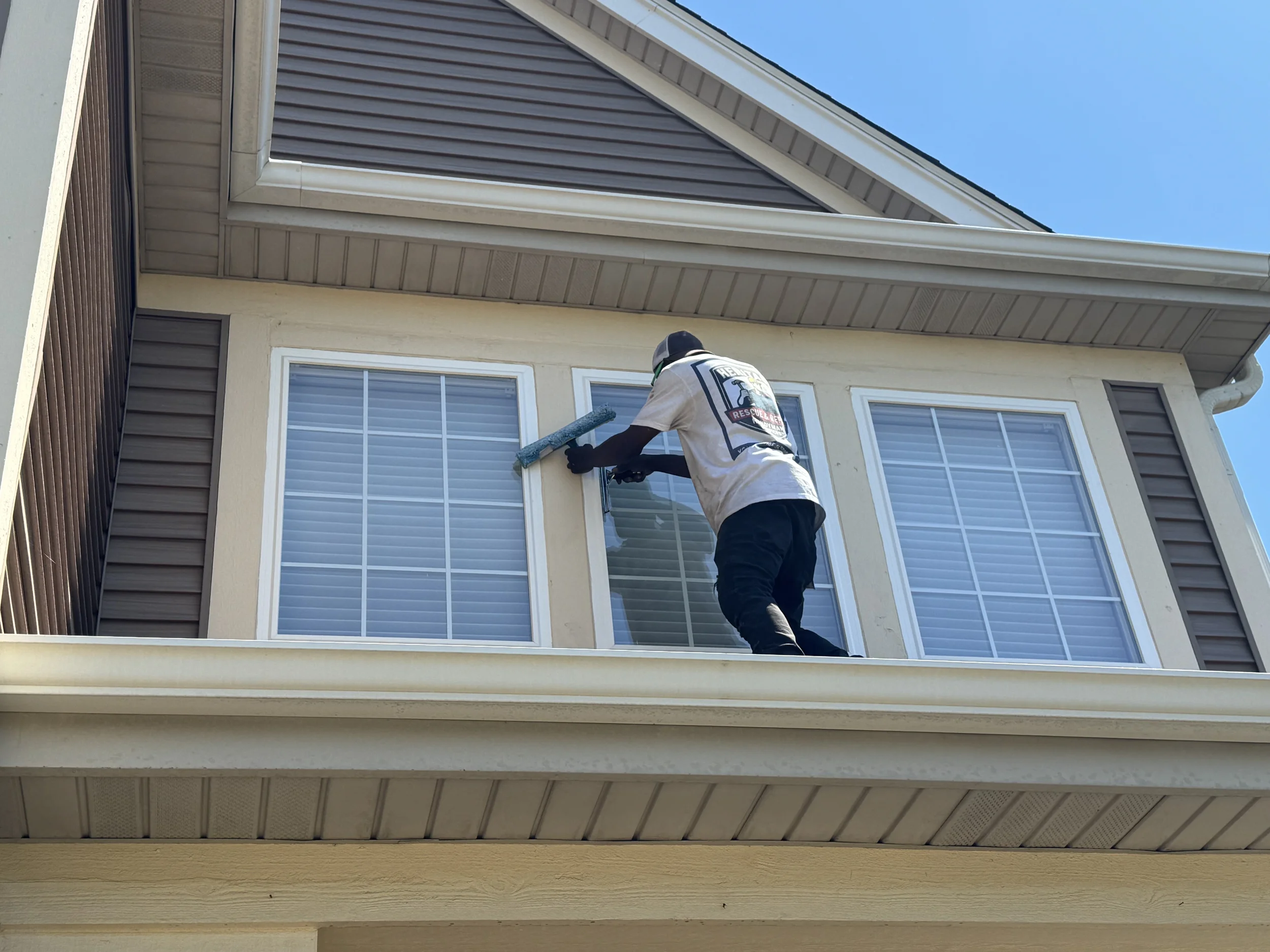 Heritage Rescue & Repair technician cleaning second-story exterior windows on a Chicagoland home.