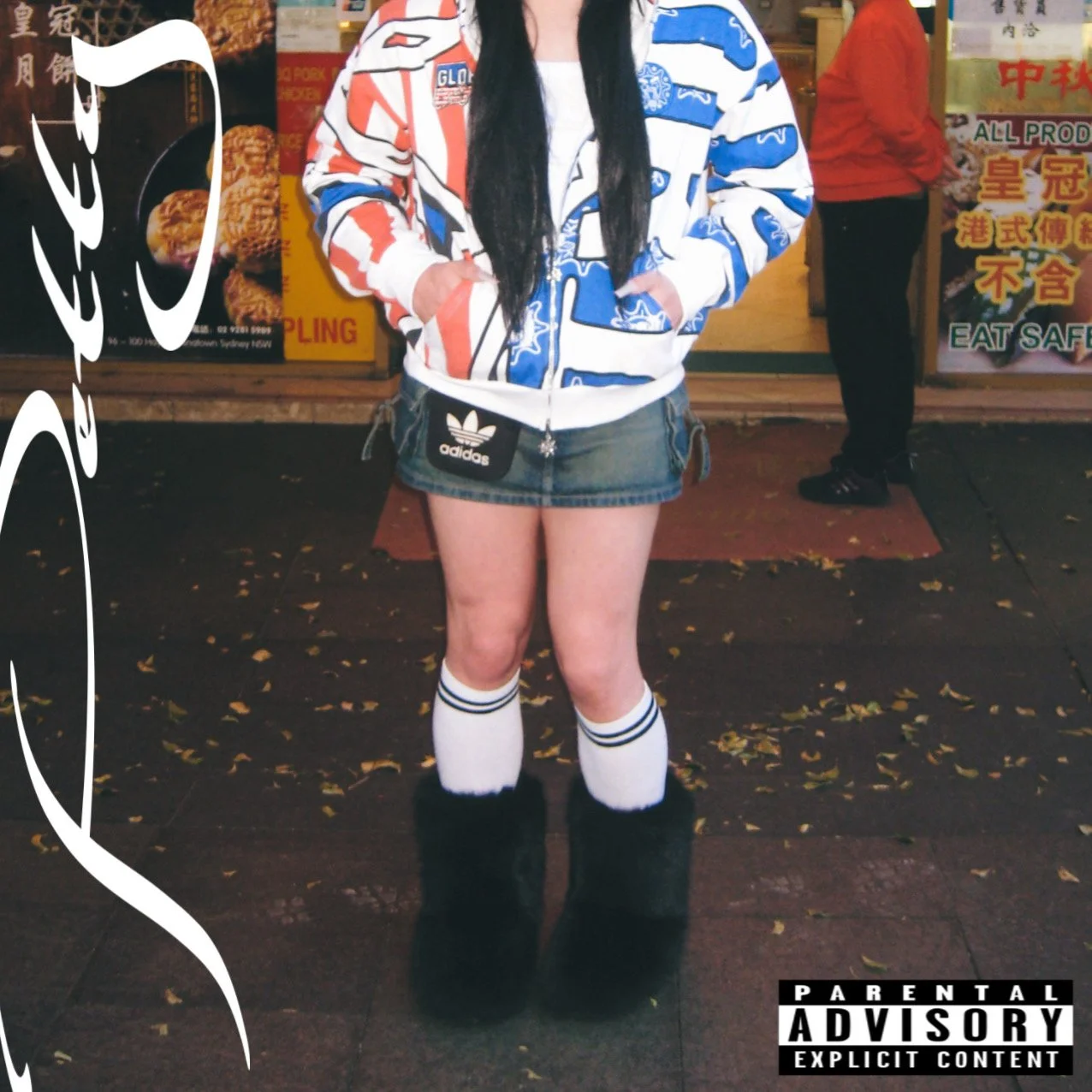 A person standing outside a store at night, wearing a colorful jacket, a denim mini skirt with an Adidas logo, knee-high socks with black stripes, and black fur-lined boots.