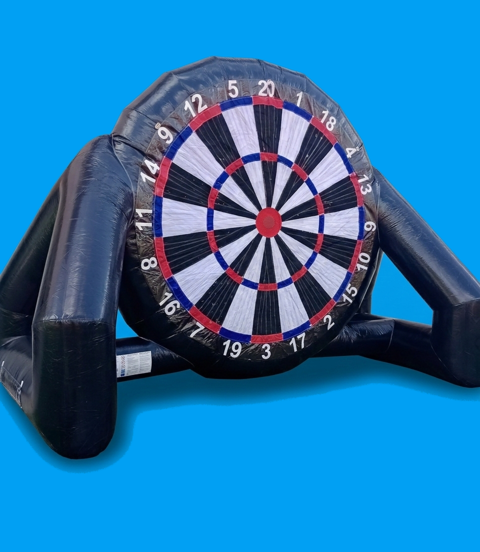 Drei Jugendliche spielen auf einem großen XXL-Dart-Spiel im Freien, mit einem schwarzen, roten, weißen und blauen Dart-Board, das an einer Wand steht.