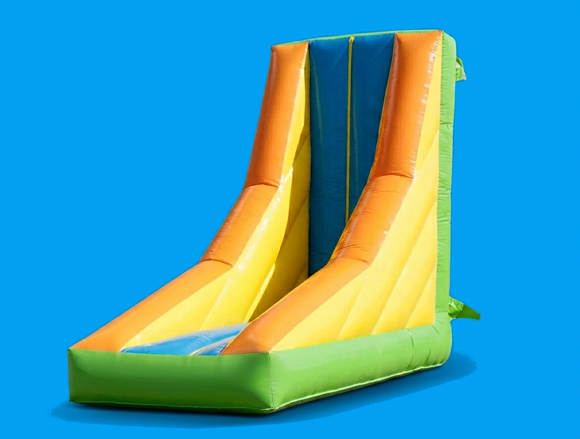 Kinder spielen auf einer bunten Wabbelmauer-Hüpfburg im Freien vor einer malerischen Bergkulisse.