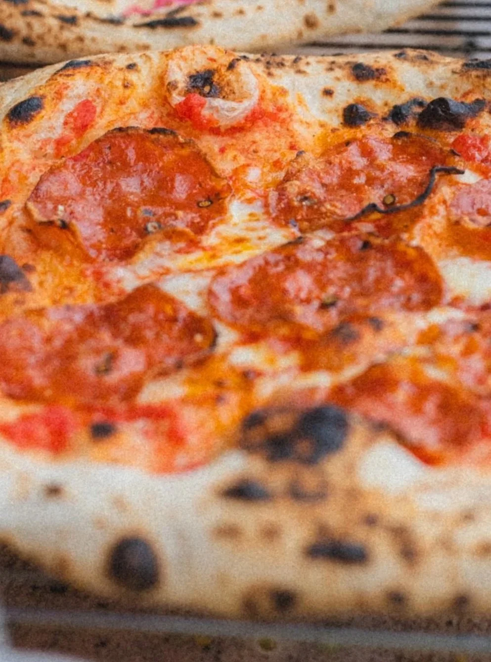 Close-up of a pepperoni pizza with a golden crust, melted cheese, and blackened spots from baking.
Nærbilde av en pepperoni pizza fra pizzakitet til Basse Pizza og Kraftgutta. Med en gylden skorpe, smeltet ost og svarte prikker  etter steking.