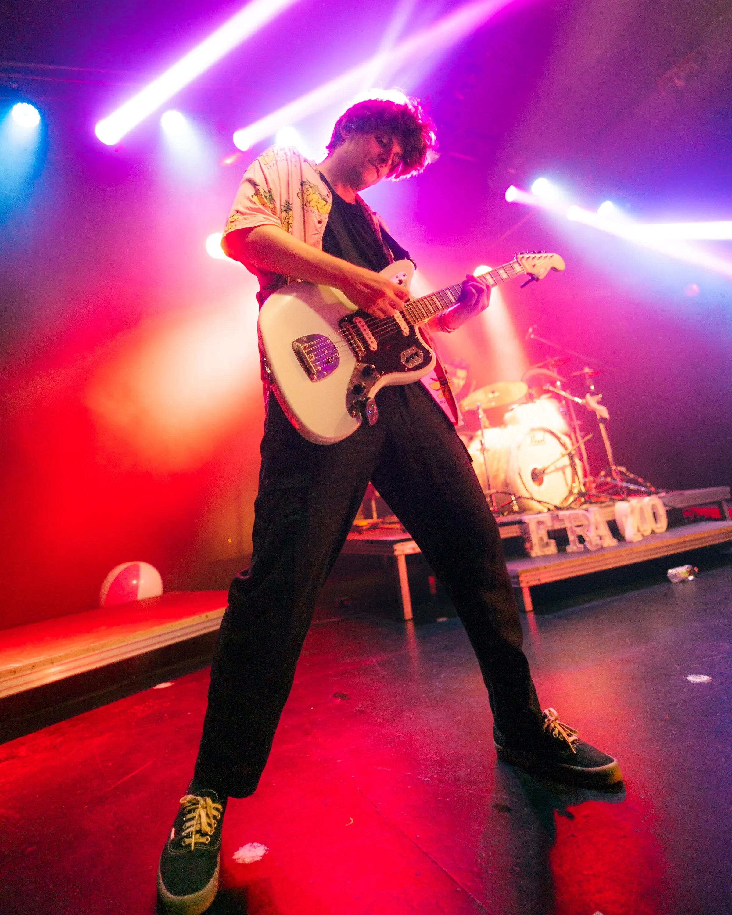 Un musicista con chitarra elettrica su palco con luci colorate