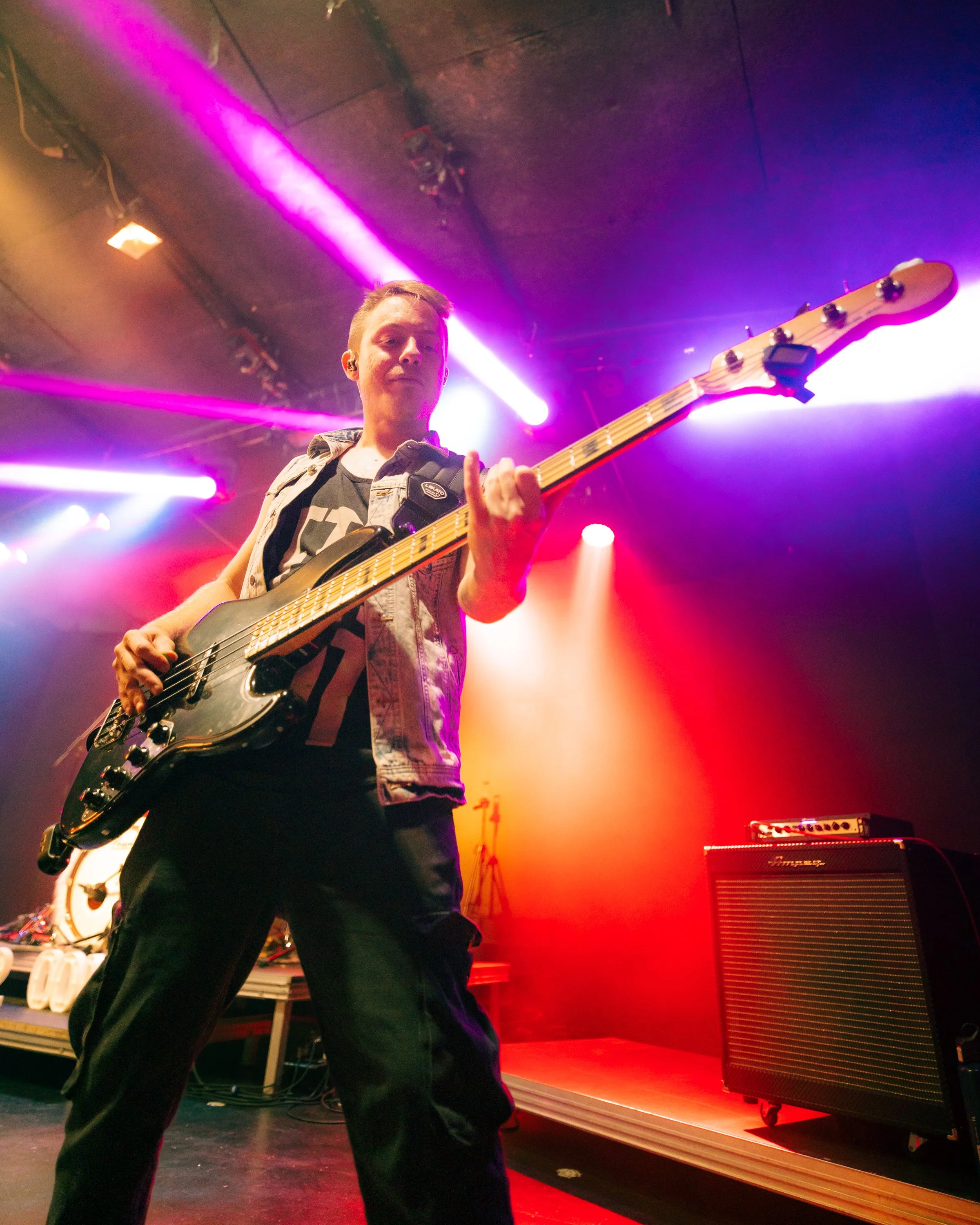 Un bassista in concerto sul palco con luci colorate e effetti di luce