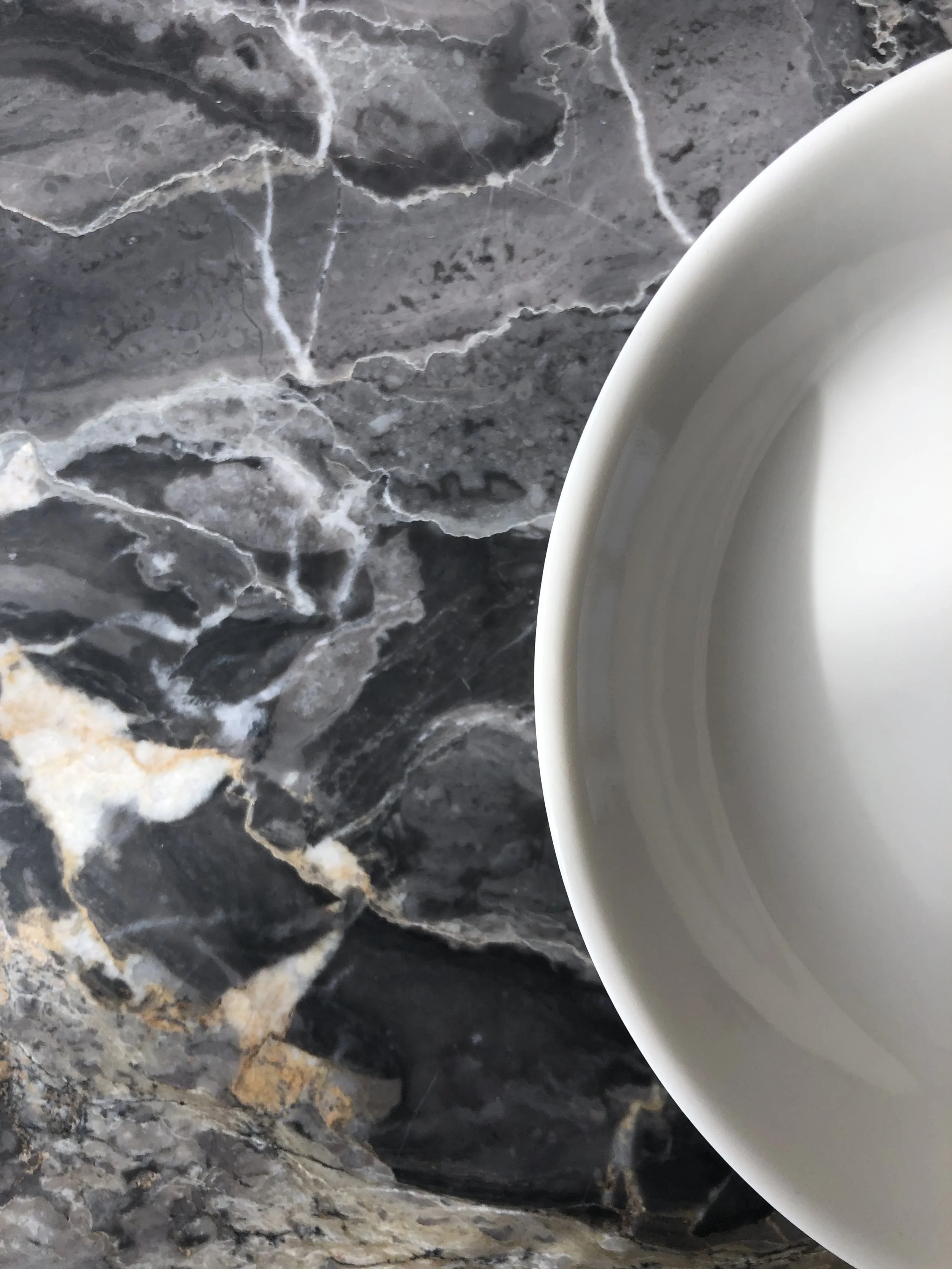 Close-up of a white ceramic bowl placed on a dark, marbled surface.