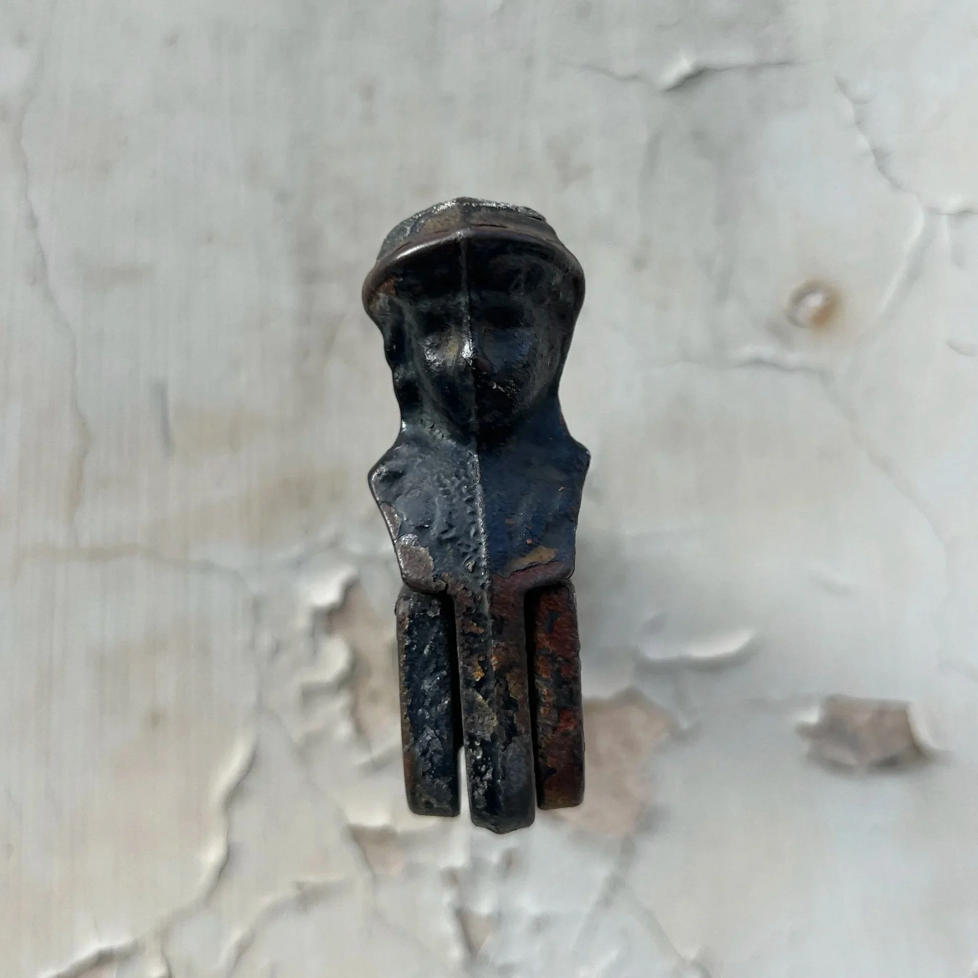 Close-up of a small, black, vintage camera with a textured surface, mounted on a wall with peeling paint.