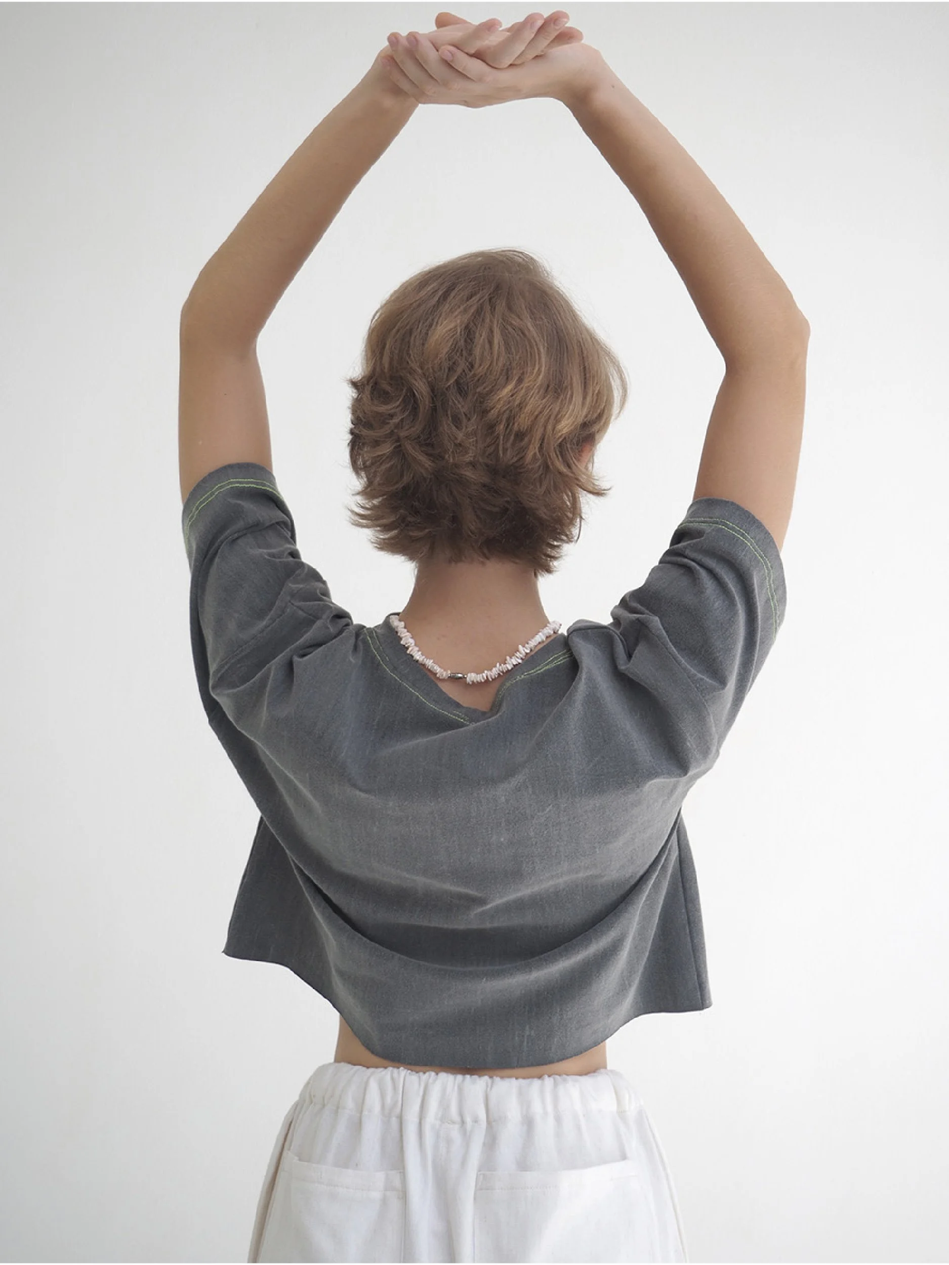 minimalist t-shirt cropped version in dark grey worn by model - back view