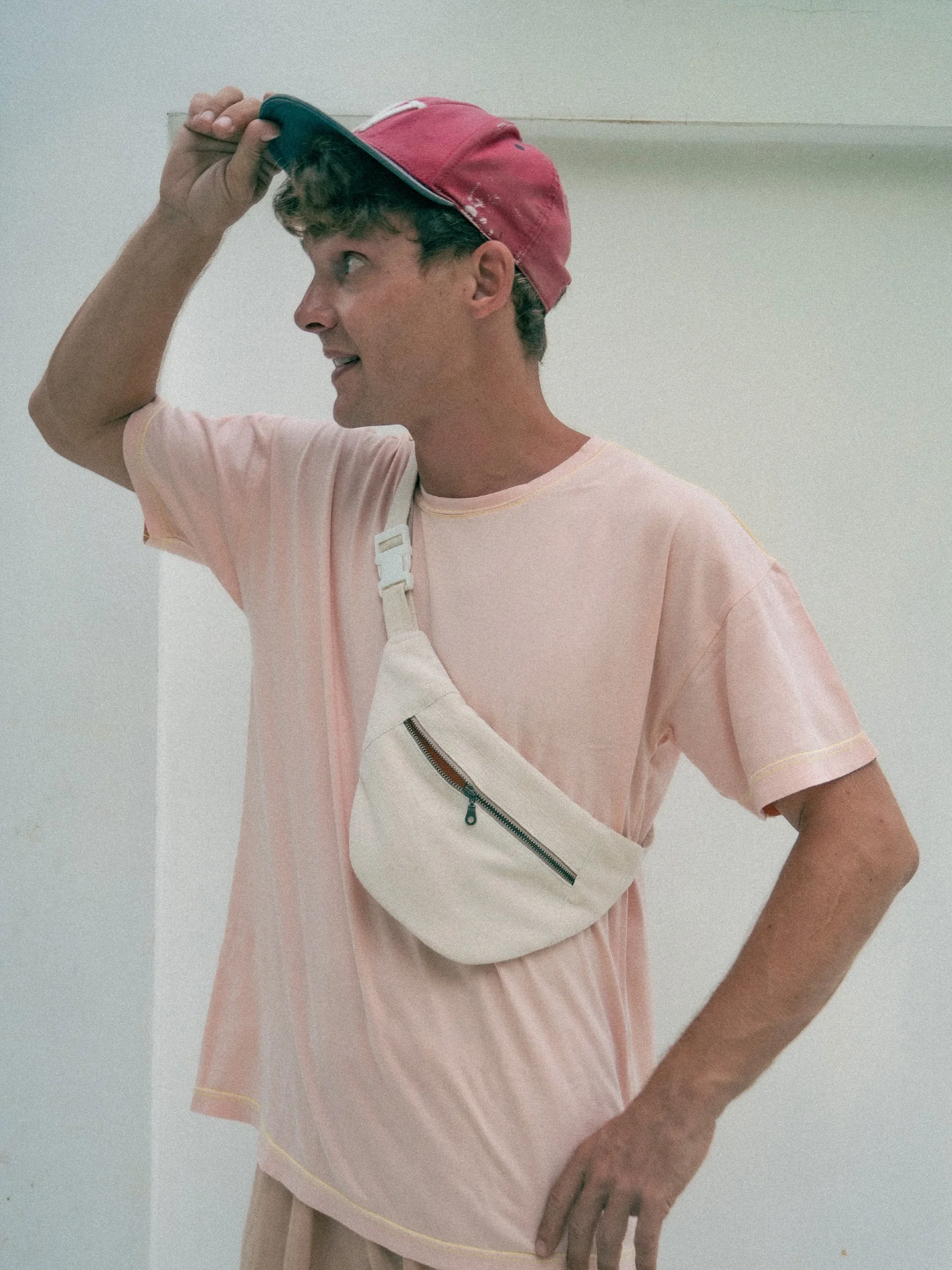 model showing off a light beige banana bag worn like a cross body bag