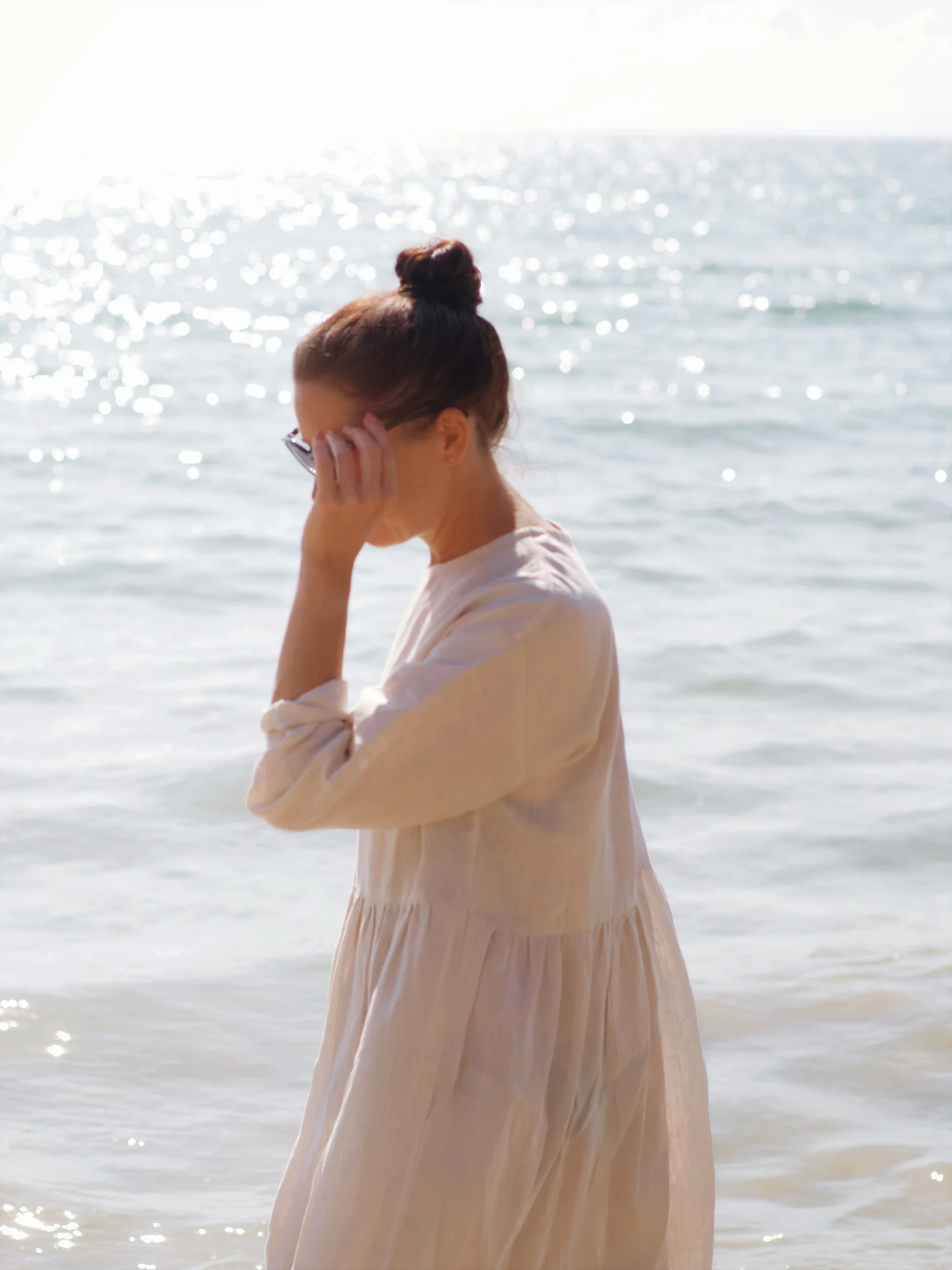 moody foto of a model wearing a lazy top dress at the beach