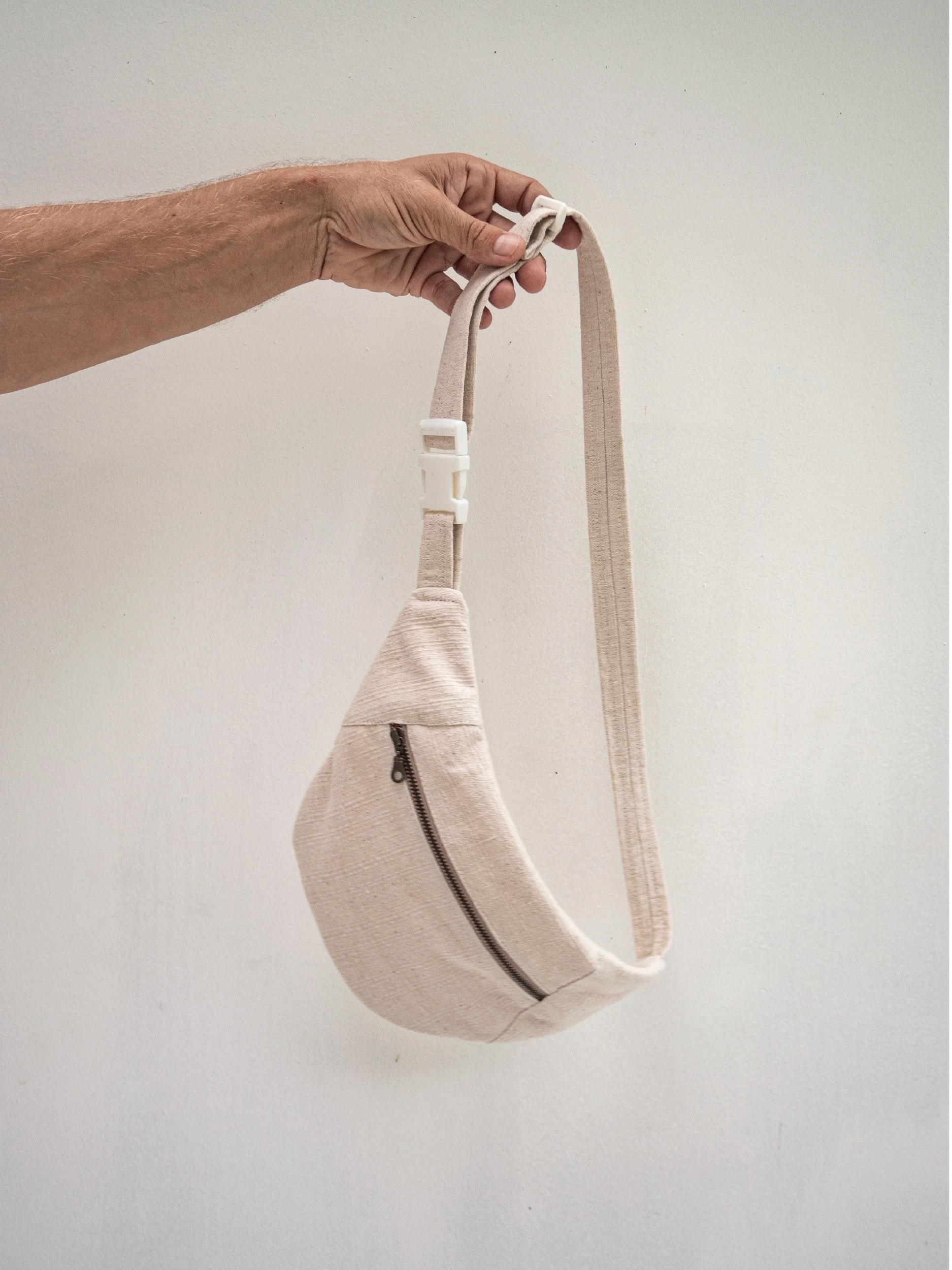 hand holding beige banana bag sample by the strap
