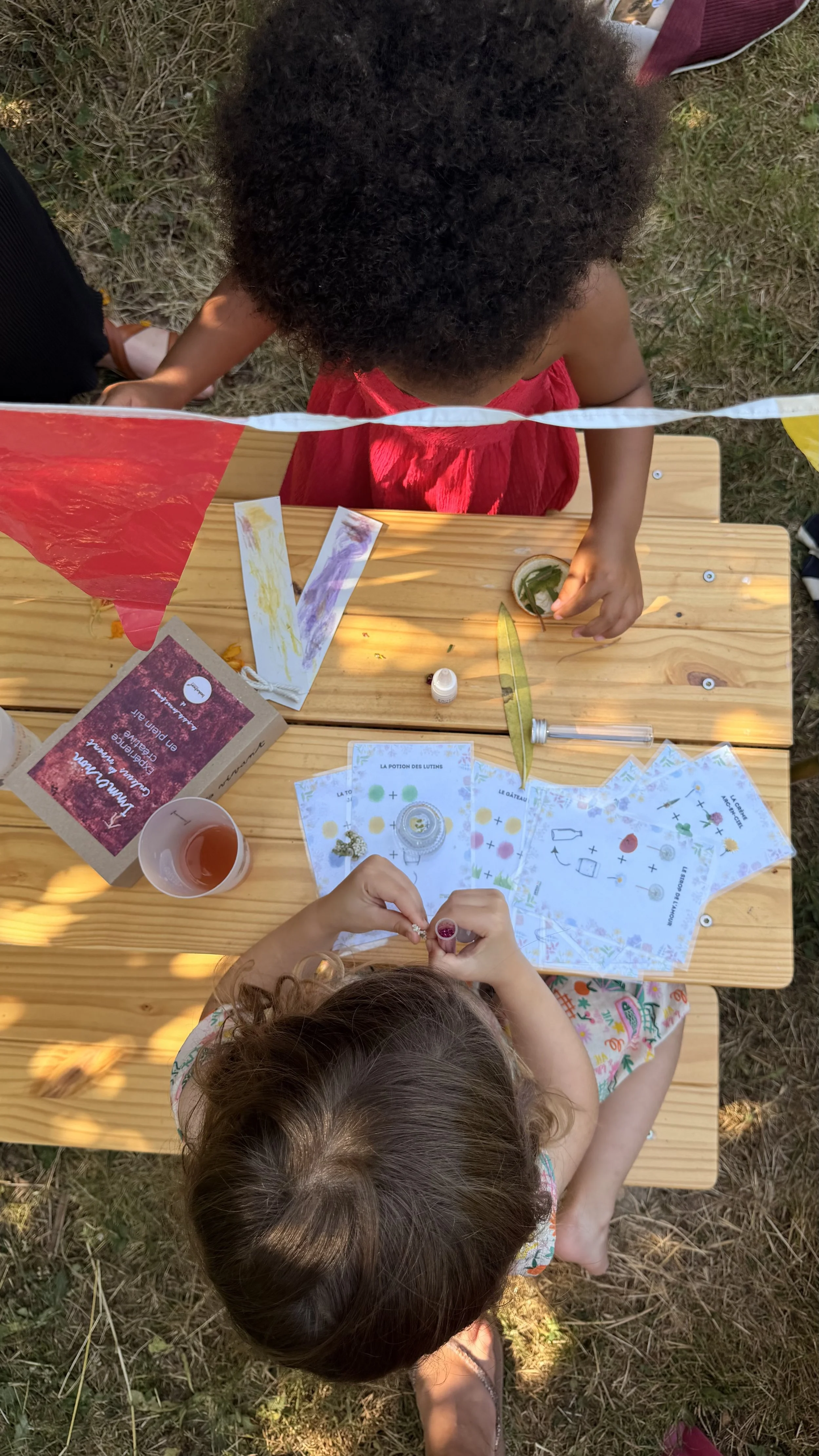 Enfants participent à une activité en extérieur, avec un tableau en bois, des feuilles,... jeux en nature